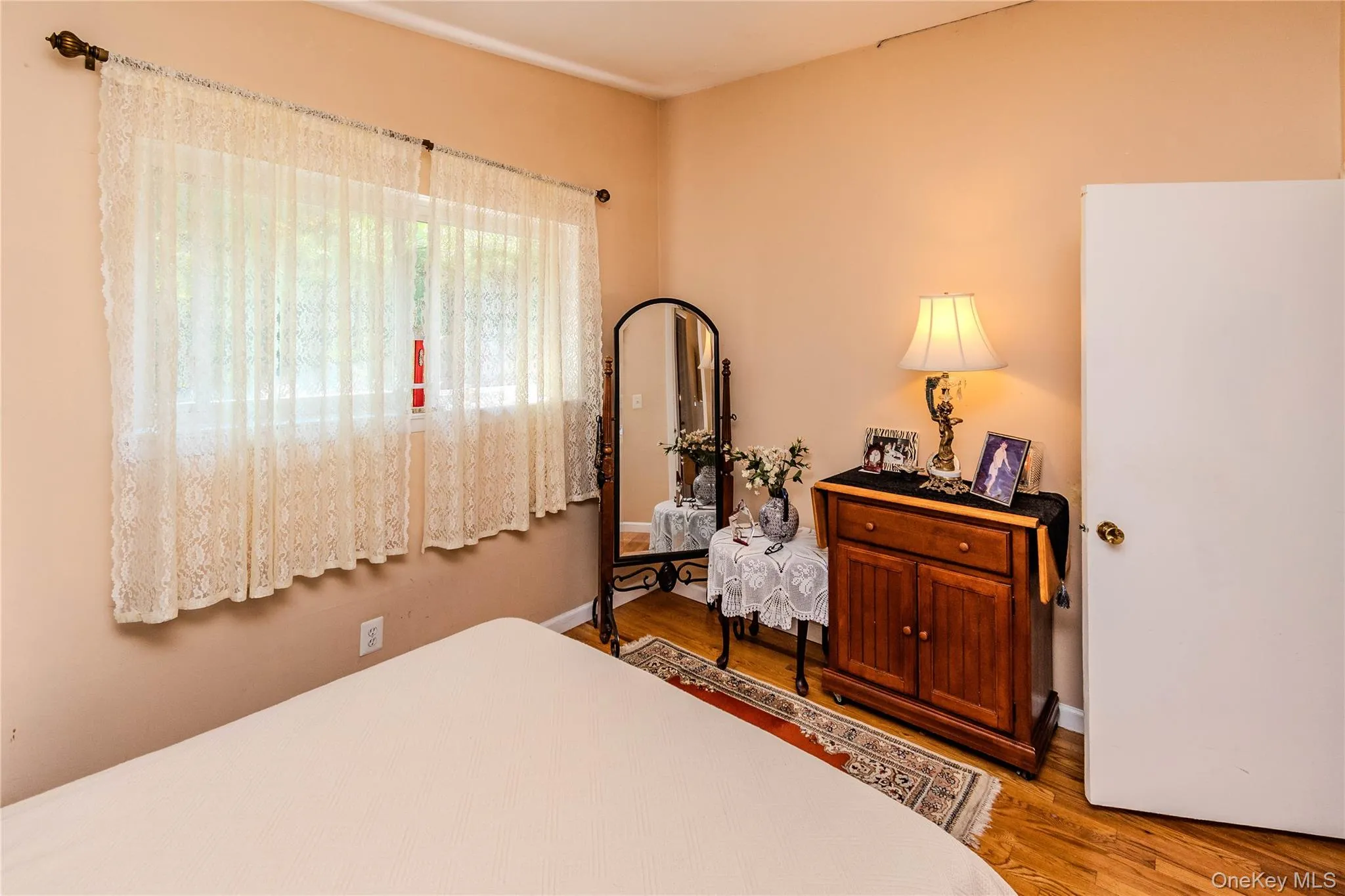 Hardwood flooring, painted walls, and a white door with a brass-toned knob Hardwood flooring, painted walls, and a white door with a brass-toned knob