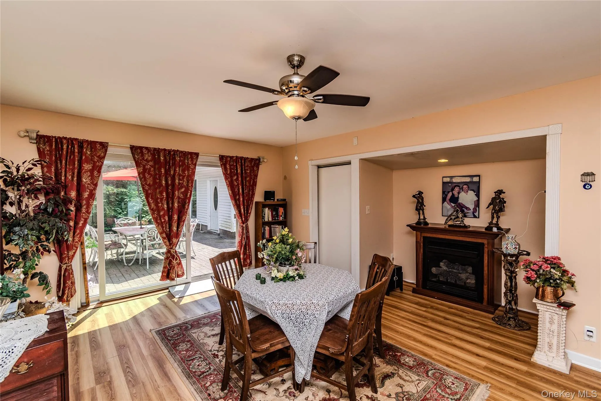 Wood-finish flooring throughout, ceiling fan with integrated lighting, built-in fireplace, and sliding glass doors leading to the exterior Wood-finish flooring throughout, ceiling fan with integrated lighting, built-in fireplace, and sliding glass doors leading to the exterior