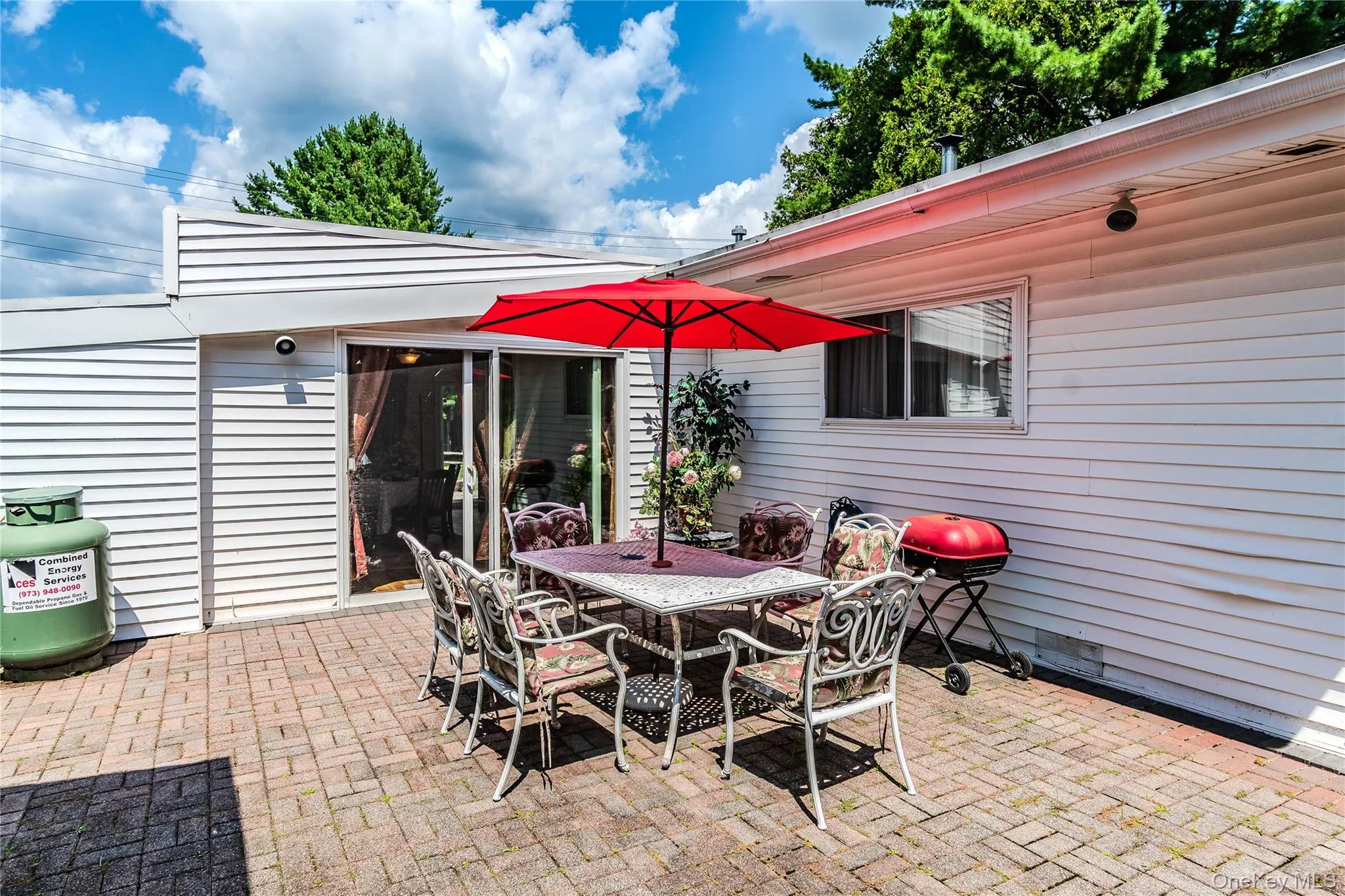 Paved brick patio with white siding exterior and sliding glass door access Paved brick patio with white siding exterior and sliding glass door access