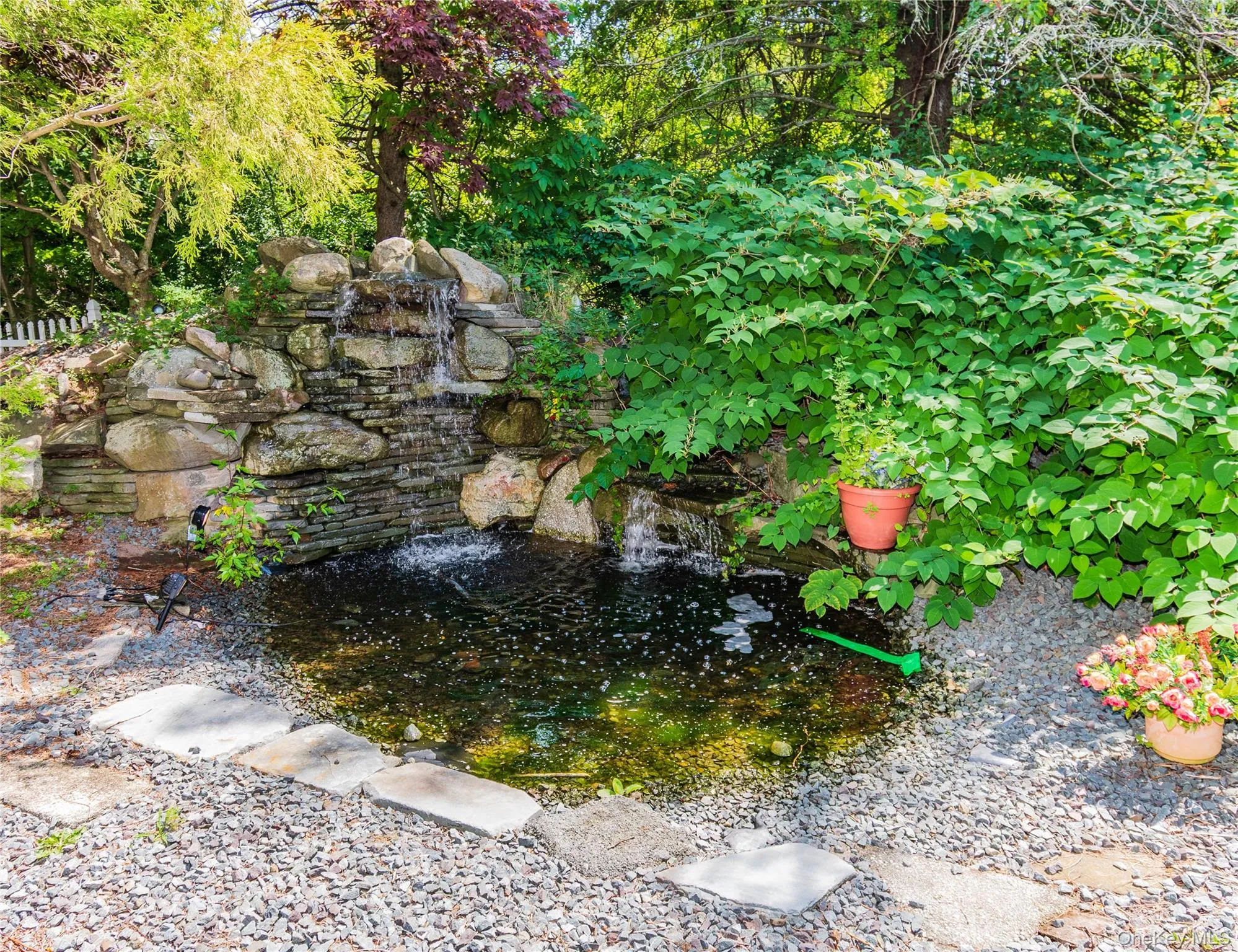 Serene backyard retreat featuring a naturalistic pond with cascading stone waterfall, surrounded by mature landscaping and lush greenery Serene backyard retreat featuring a naturalistic pond with cascading stone waterfall, surrounded by mature landscaping and lush greenery