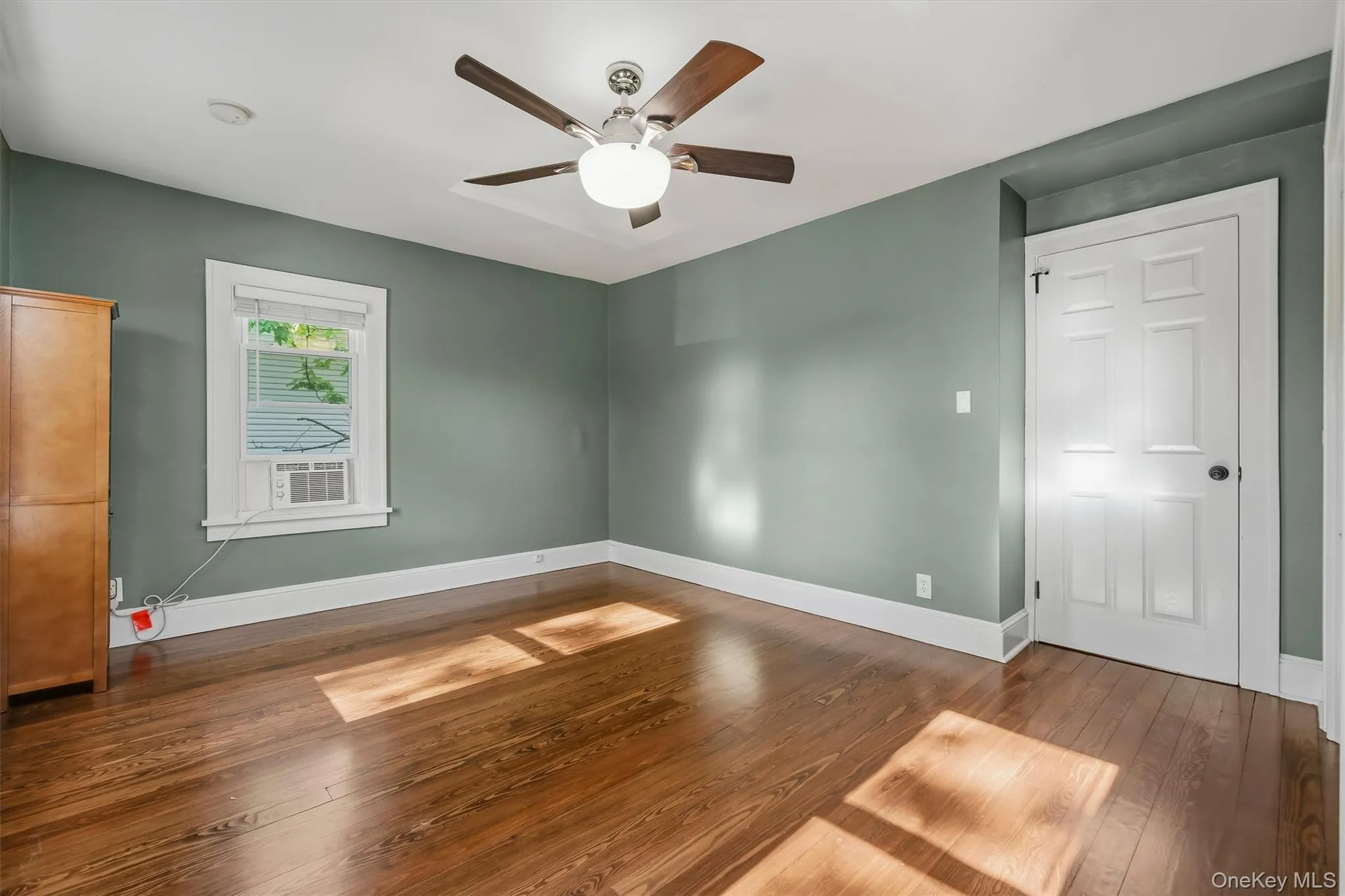 Hardwood flooring, painted walls, ceiling fan with light fixture, window with blinds, panel door Hardwood flooring, painted walls, ceiling fan with light fixture, window with blinds, panel door
