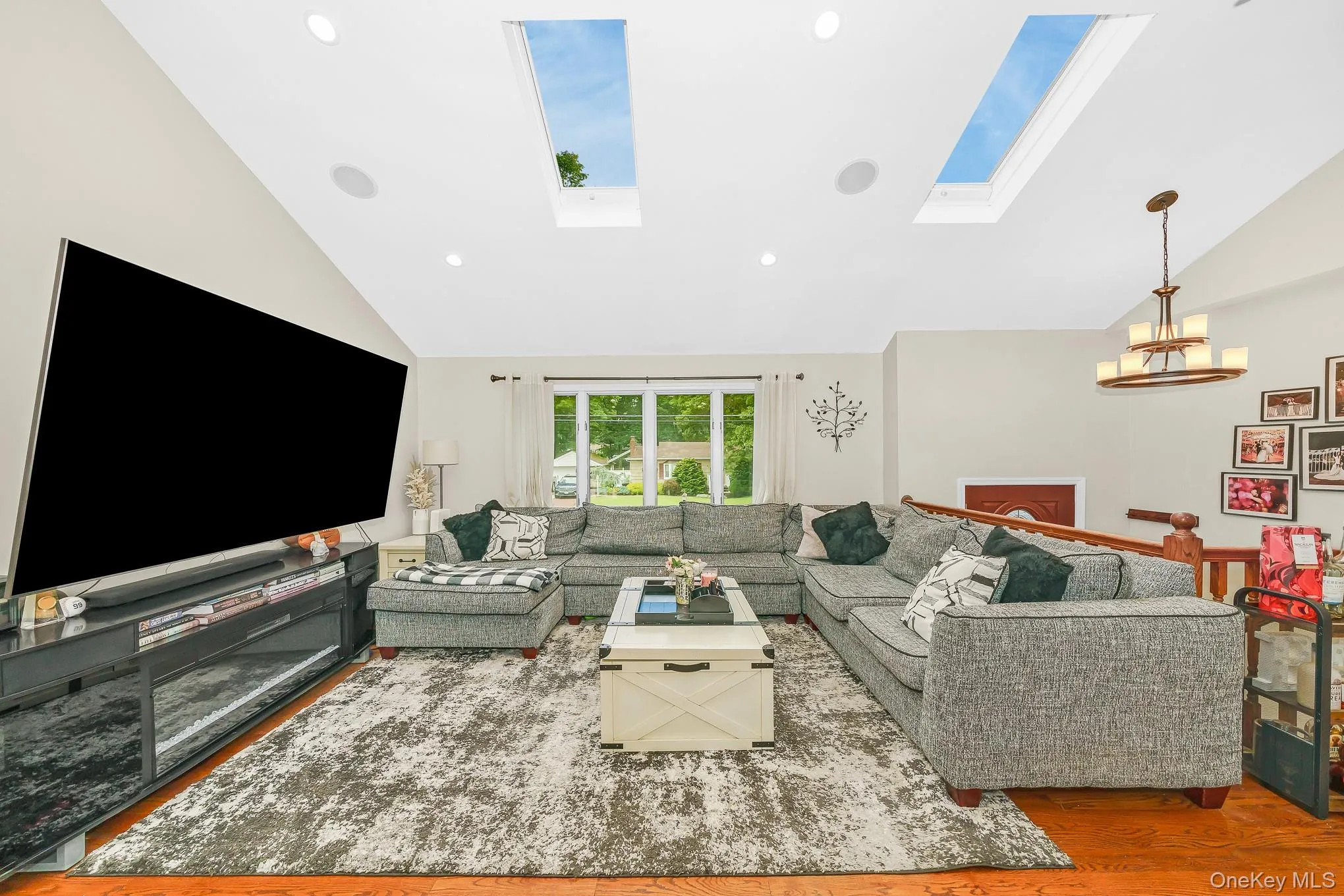Vaulted ceiling with skylights, recessed lighting, wood-finish flooring, and a multi-pane window Vaulted ceiling with skylights, recessed lighting, wood-finish flooring, and a multi-pane window