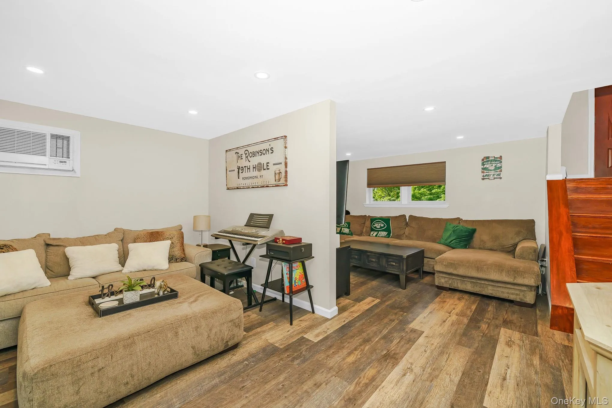 Finished lower level with wood-finish flooring, recessed lighting, and a window air conditioning unit Finished lower level with wood-finish flooring, recessed lighting, and a window air conditioning unit