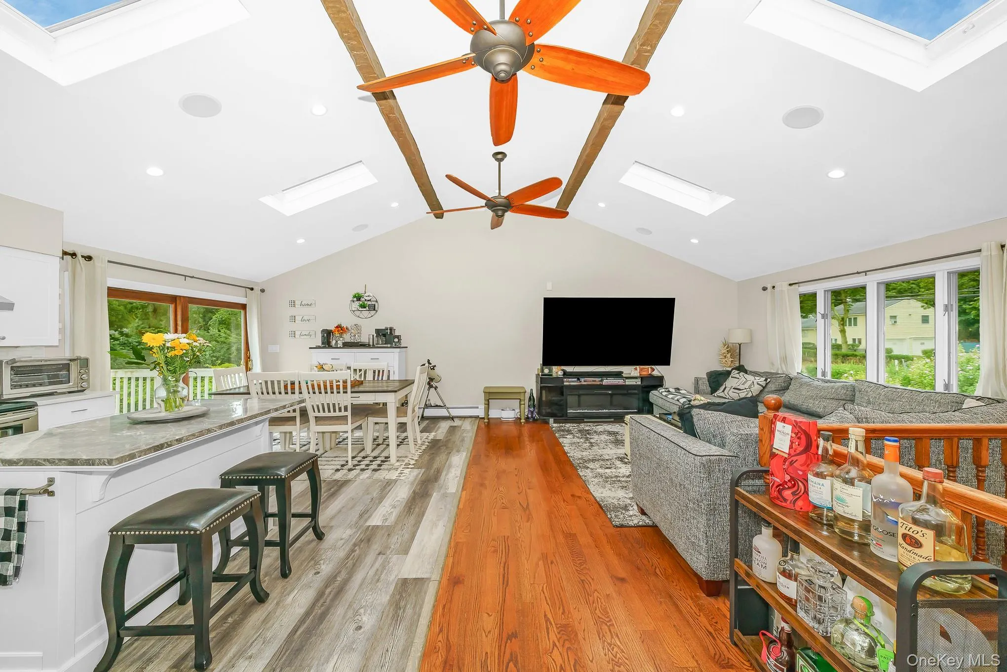 Vaulted ceiling with exposed wood beams and skylights, recessed lighting, wood-finish flooring, and a kitchen island with a stone countertop featuring the open concept Vaulted ceiling with exposed wood beams and skylights, recessed lighting, wood-finish flooring, and a kitchen island with a stone countertop featuring the open concept