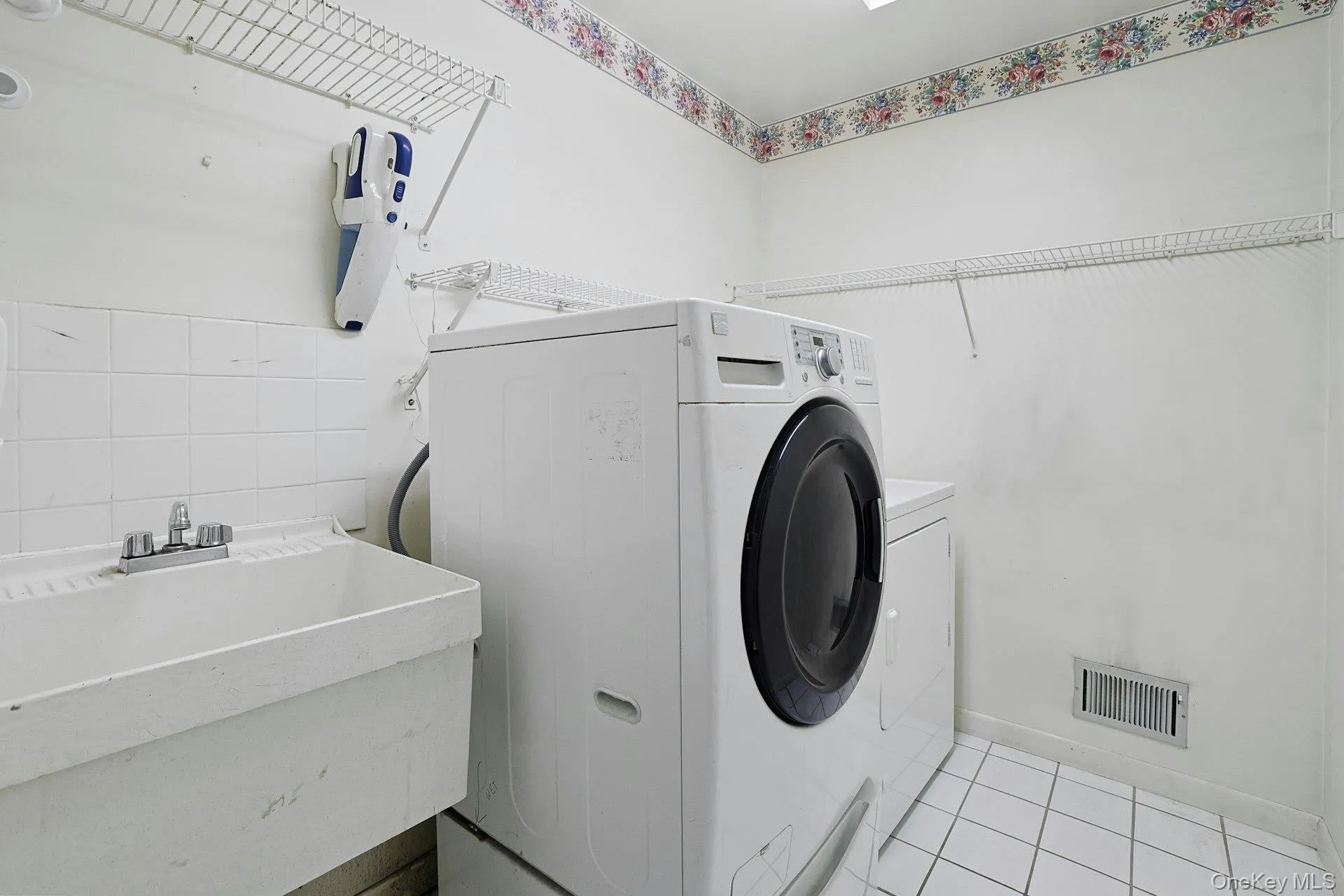 Laundry room featuring a sink, wire shelving, and tile flooring Laundry room featuring a sink, wire shelving, and tile flooring