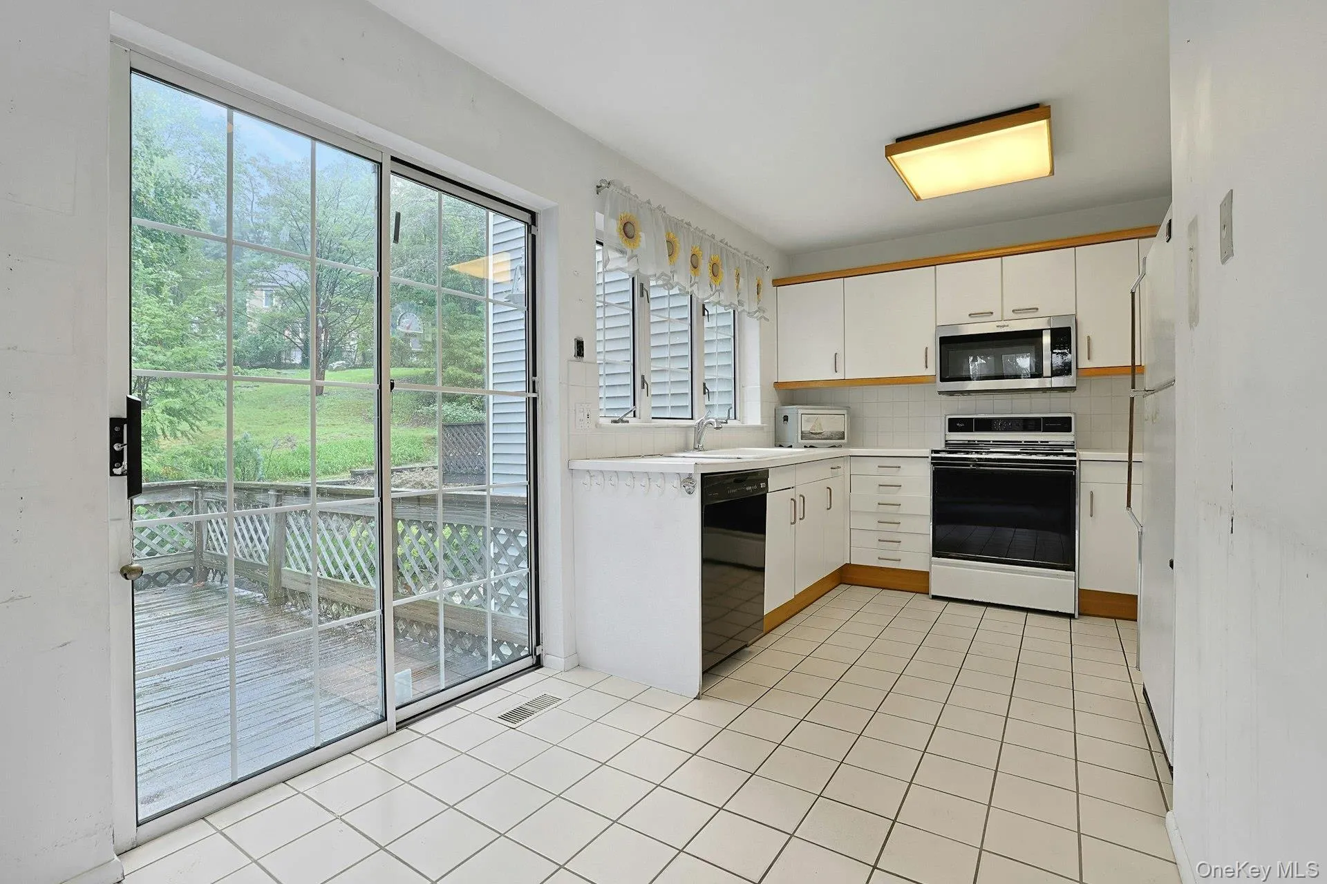 Kitchen featuring white cabinetry, sliding glass door to deck Kitchen featuring white cabinetry, sliding glass door to deck