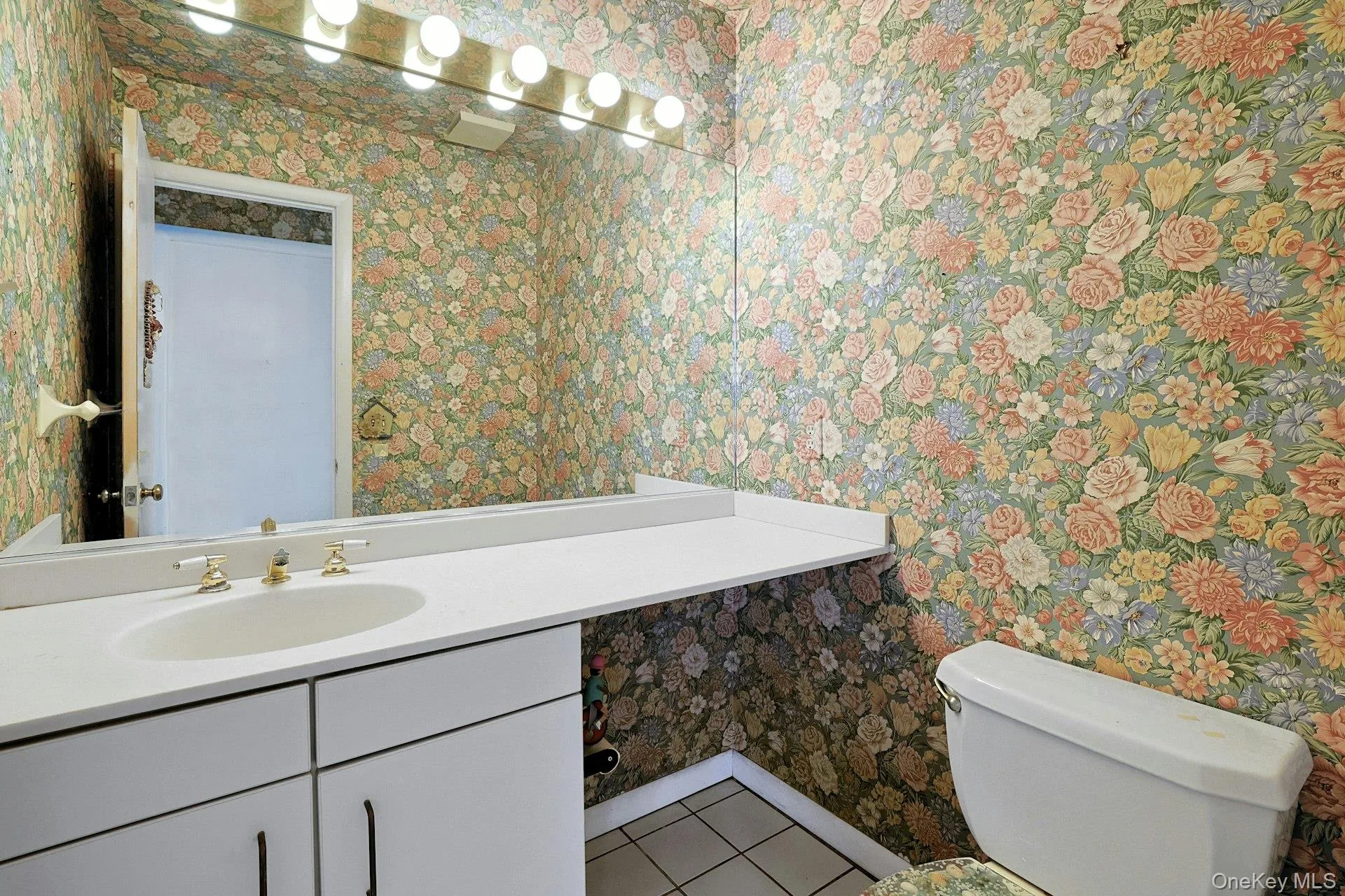Powder rm featuring a vanity with an integrated sink, gold-tone faucet, a wall-mounted mirror, and overhead vanity lighting Powder rm featuring a vanity with an integrated sink, gold-tone faucet, a wall-mounted mirror, and overhead vanity lighting