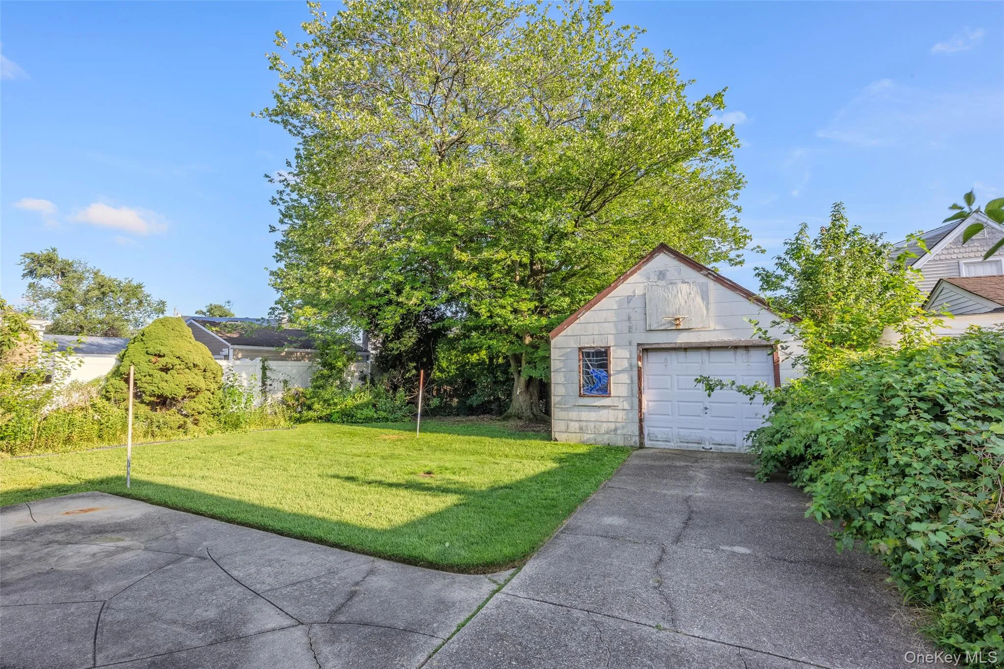 Detached garage with a paneled door, a paved driveway, and a manicured lawn Detached garage with a paneled door, a paved driveway, and a manicured lawn