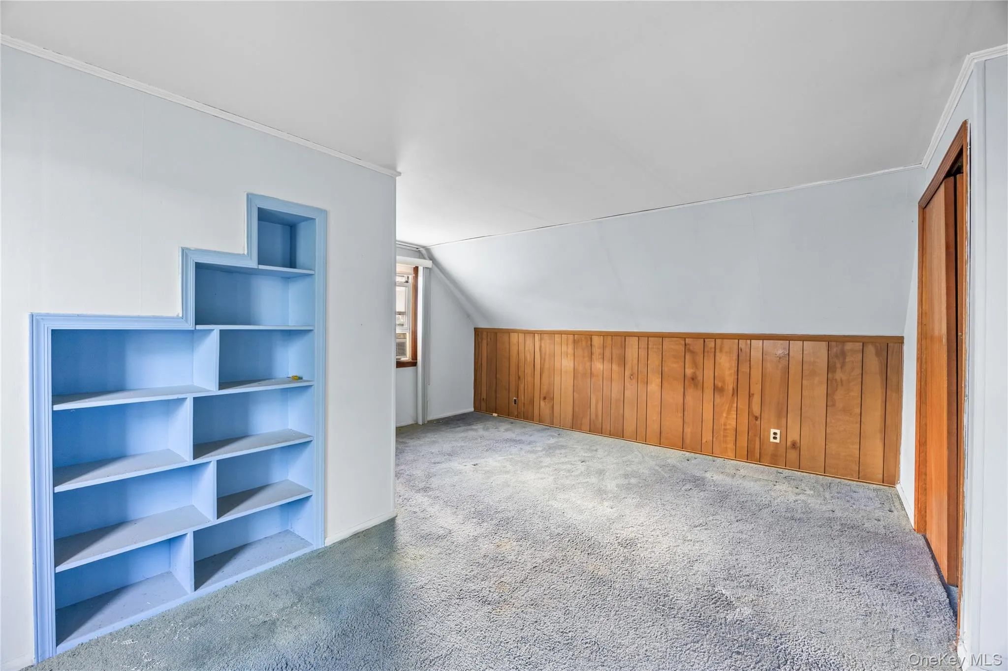 Bedroom #4: Built-in shelving, wood-paneled wall, angled ceiling, and a window with wood trim Bedroom #4: Built-in shelving, wood-paneled wall, angled ceiling, and a window with wood trim