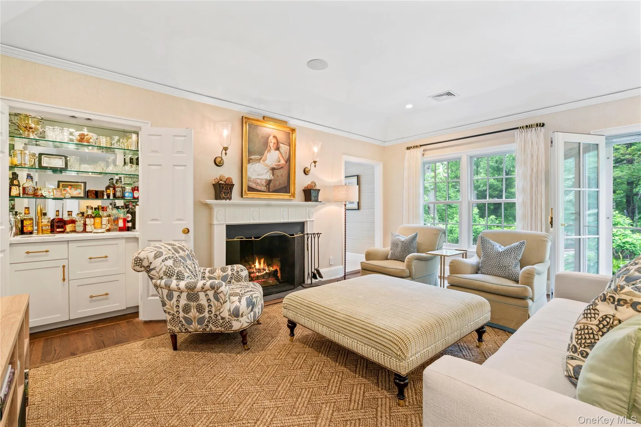 Light filled Living room featuring crown molding, wood finished floors, a fireplace and a dry bar. Light filled Living room featuring crown molding, wood finished floors, a fireplace and a dry bar.