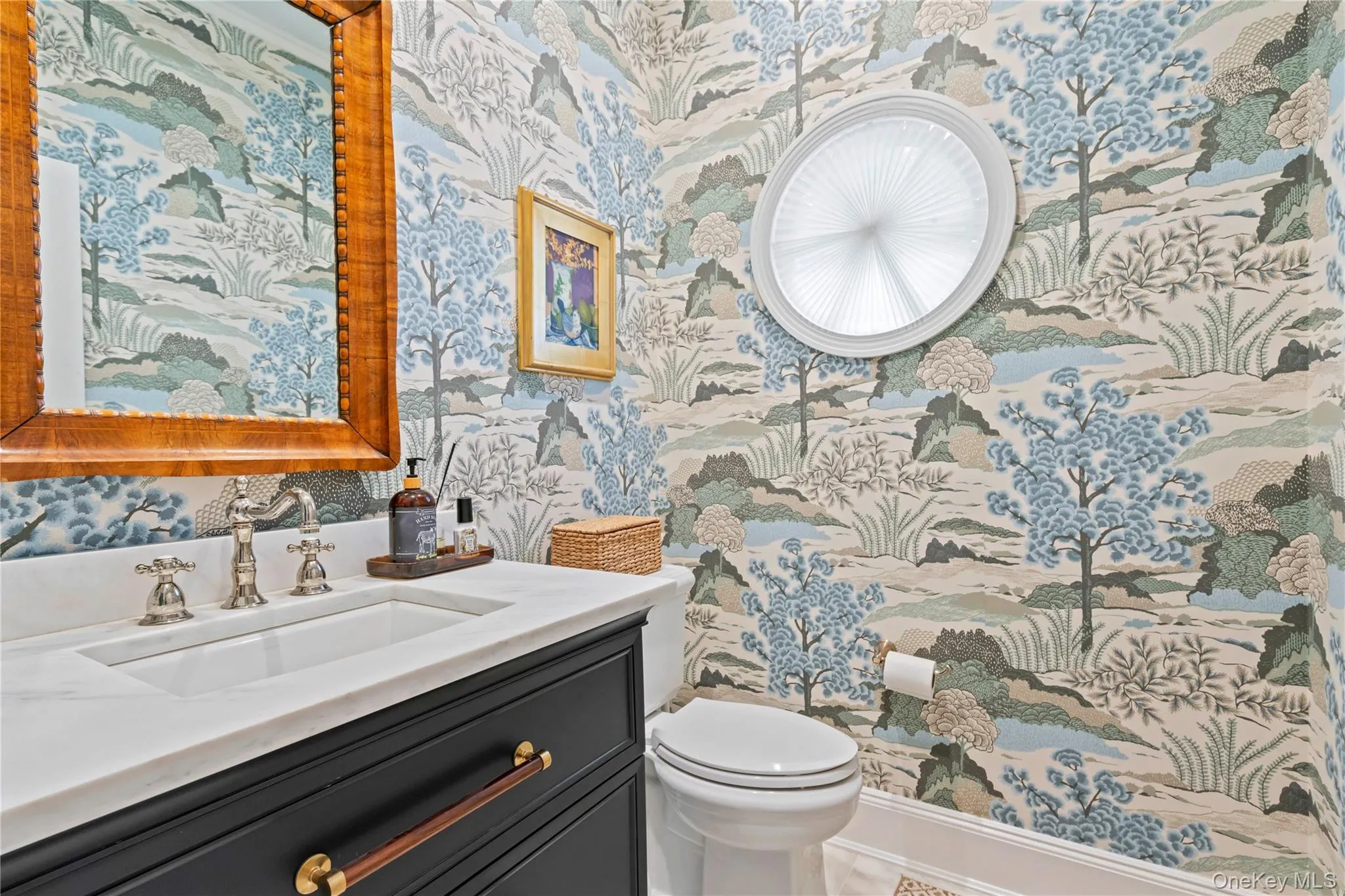 Half bathroom with wallpapered walls, vanity, and toilet off the entrance foyer. Half bathroom with wallpapered walls, vanity, and toilet off the entrance foyer.