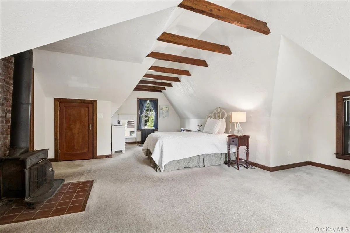 Another View of the Primary Bedroom Showing the Wood-Burning Fireplace and Exposed Beams Another View of the Primary Bedroom Showing the Wood-Burning Fireplace and Exposed Beams