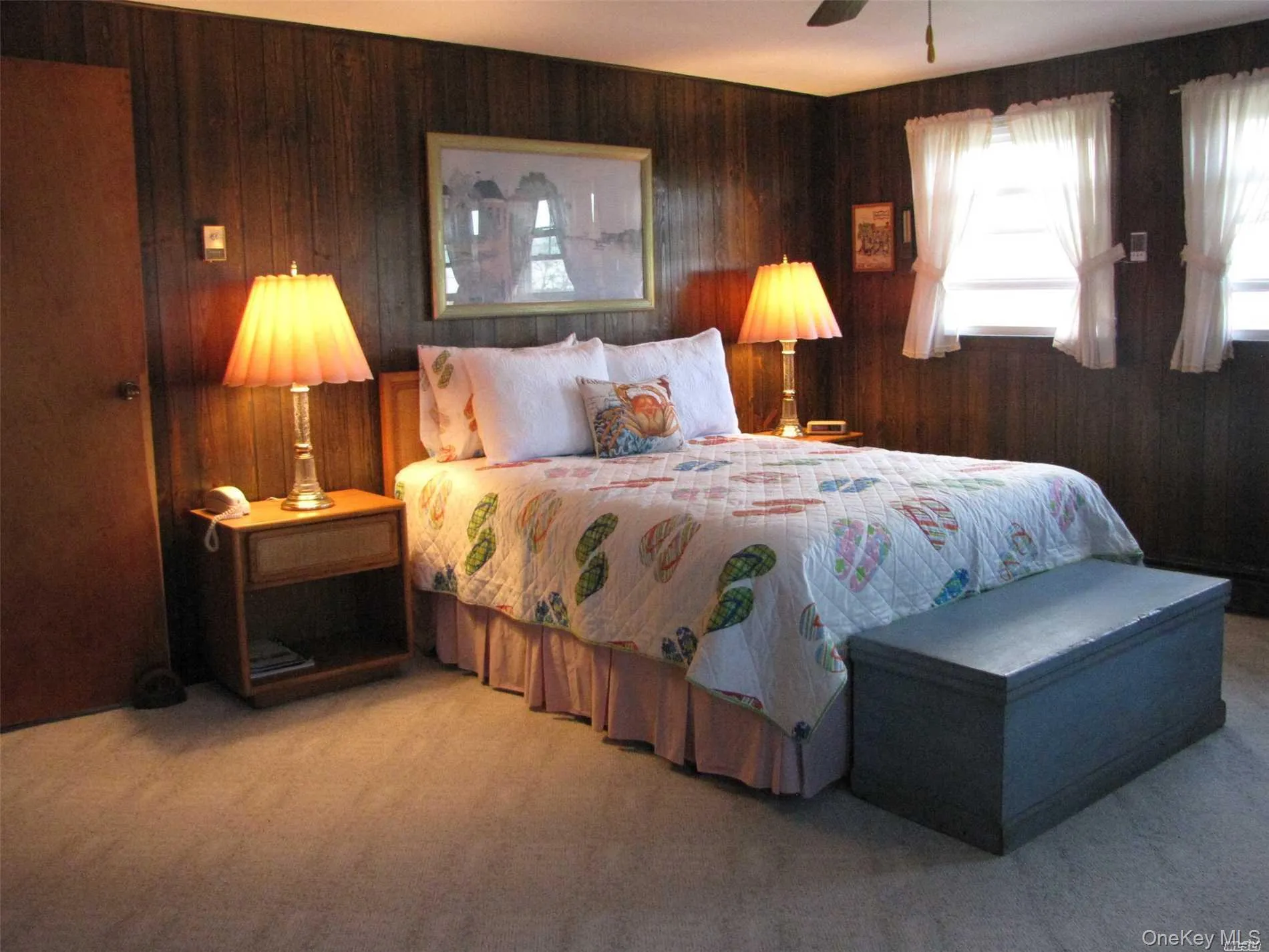 Carpeted bedroom with wood walls and a ceiling fan Carpeted bedroom with wood walls and a ceiling fan