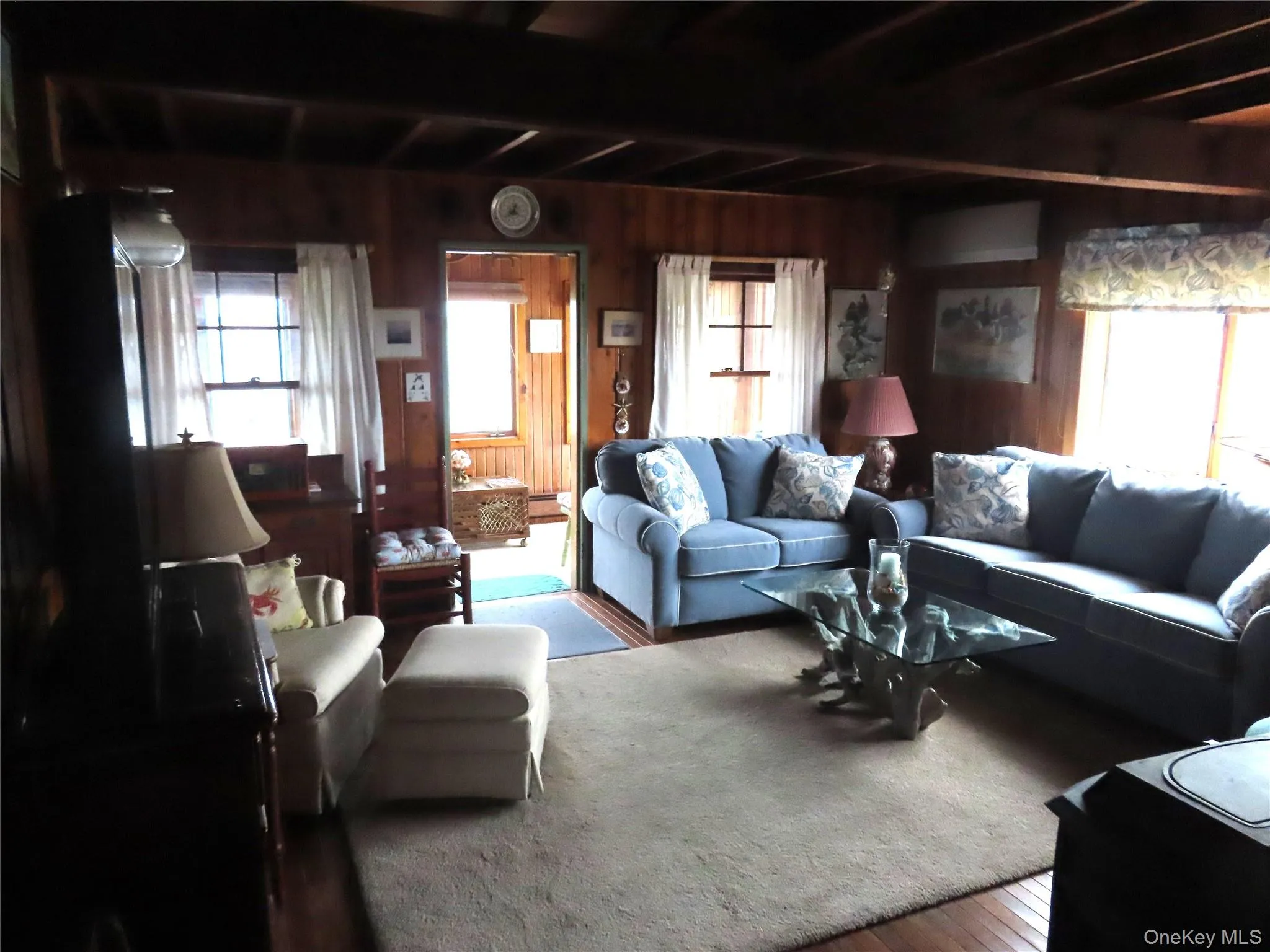 Living area featuring wood walls, beam ceiling, and wood finished floors Living area featuring wood walls, beam ceiling, and wood finished floors