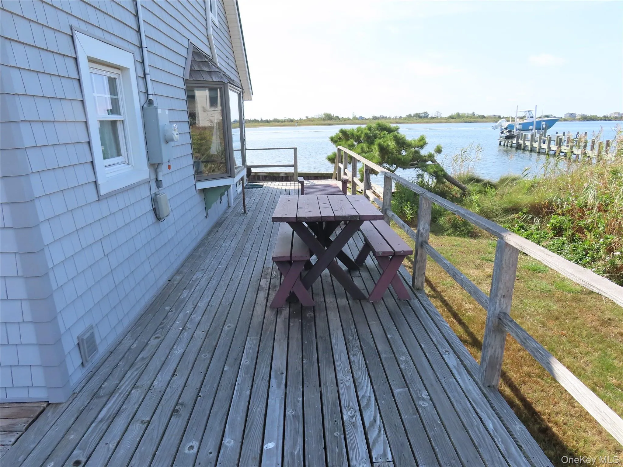 Wooden deck with a water view, outdoor dining space, and a yard Wooden deck with a water view, outdoor dining space, and a yard