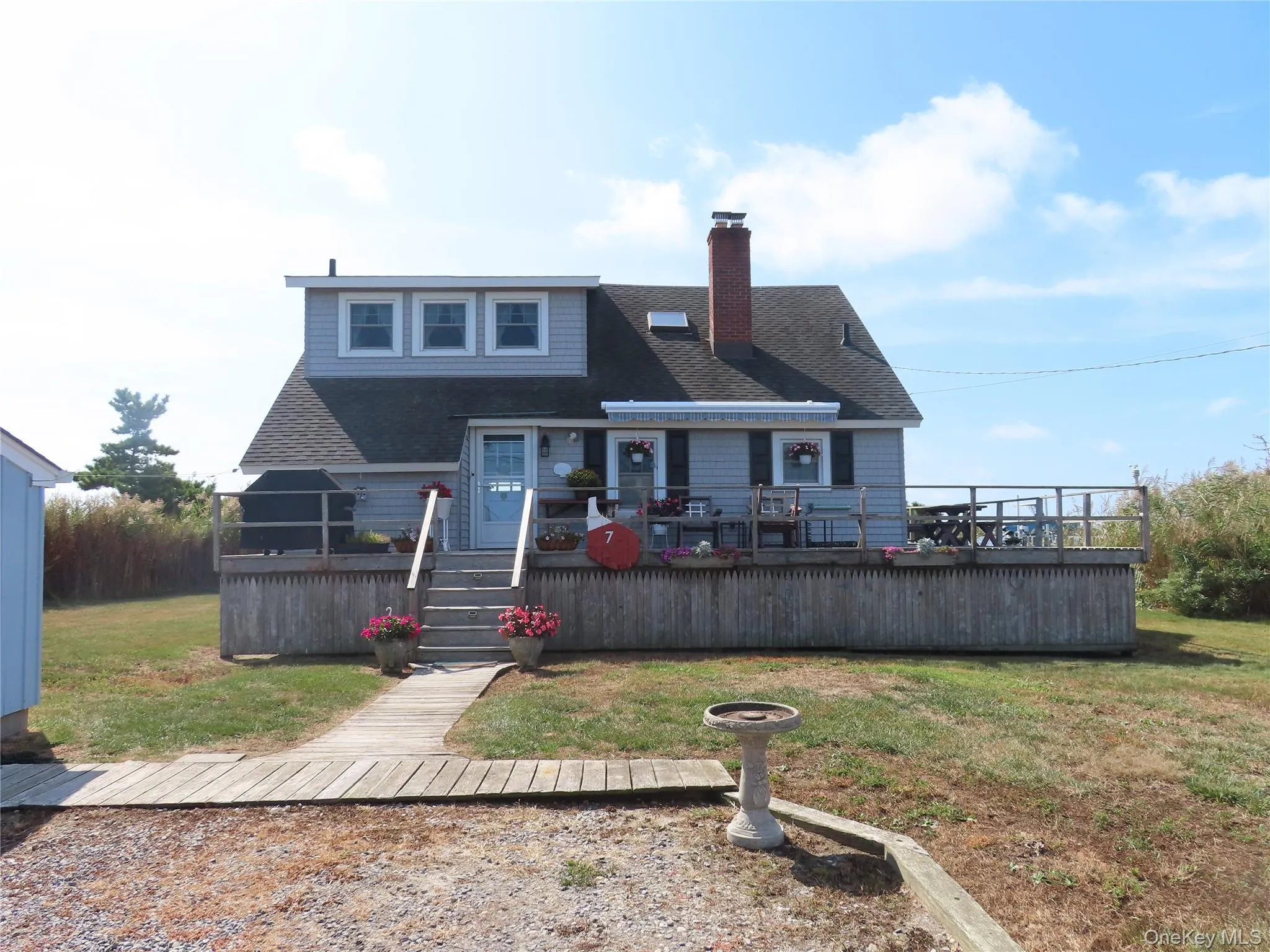 Back of house featuring a wooden deck, a shingled roof, a yard, and a chimney Back of house featuring a wooden deck, a shingled roof, a yard, and a chimney