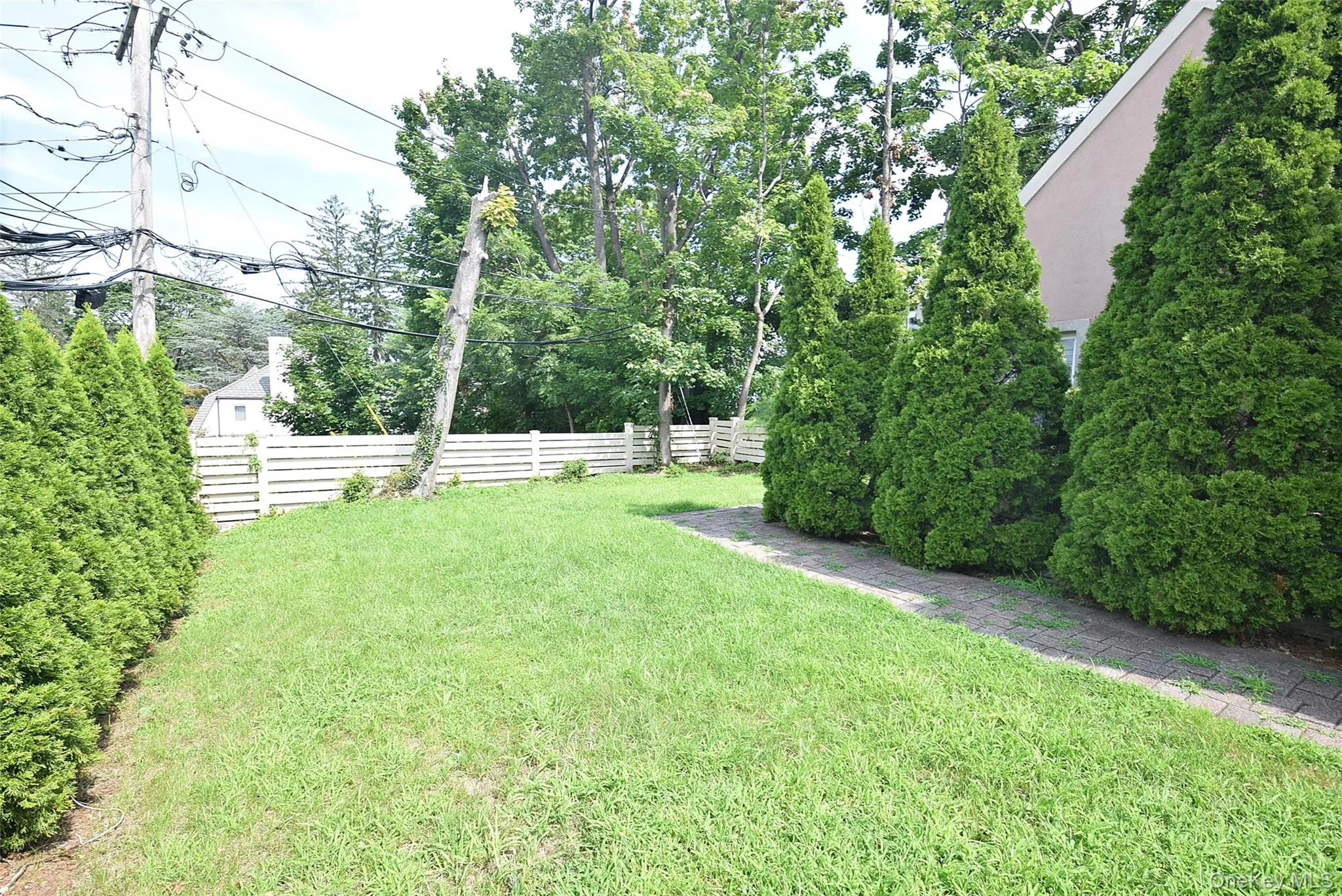 Expansive lawn bordered by a white horizontal slat fence Expansive lawn bordered by a white horizontal slat fence
