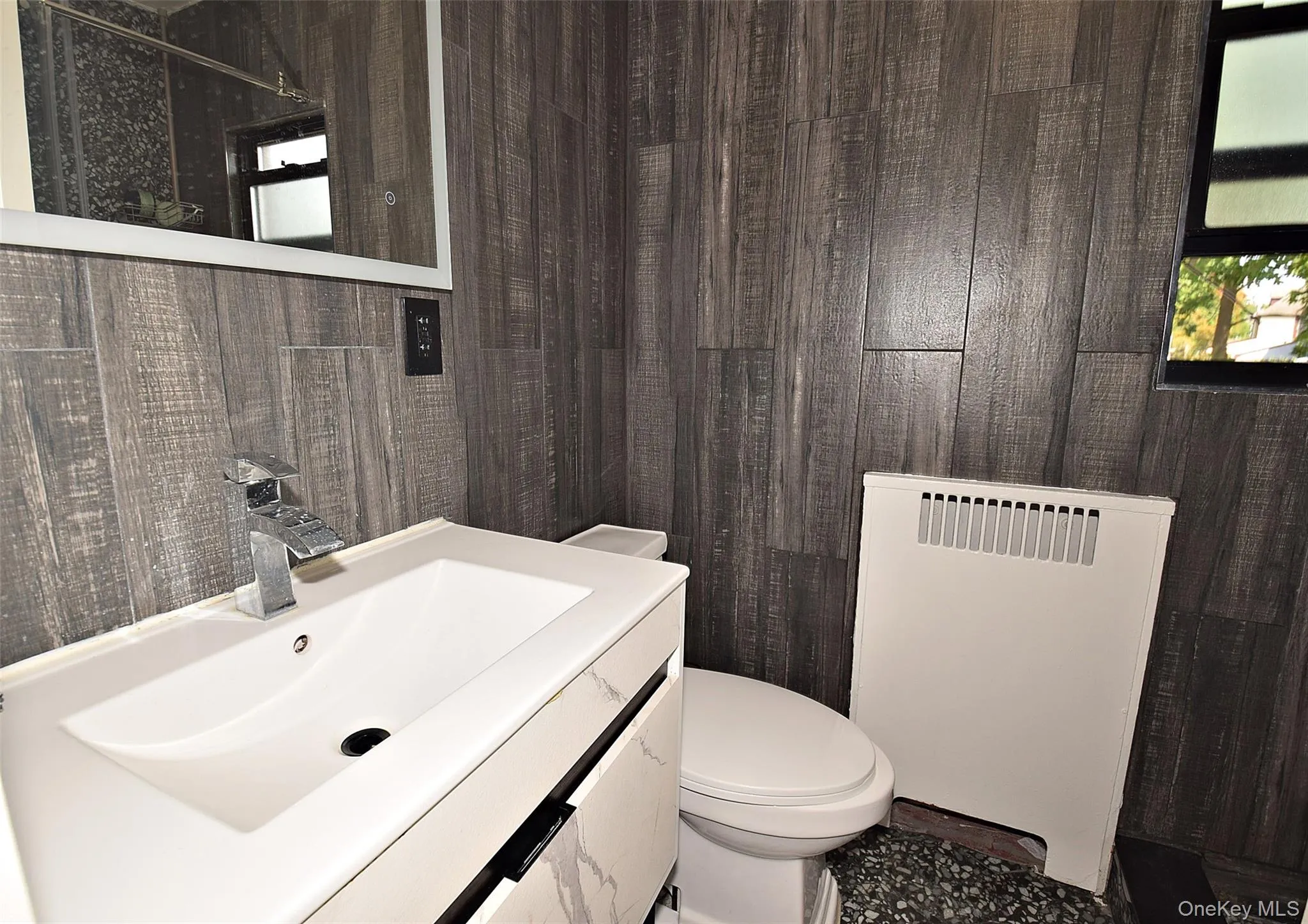 Vanity with integrated white basin, chrome faucet, and gray wood-finish wall paneling Vanity with integrated white basin, chrome faucet, and gray wood-finish wall paneling