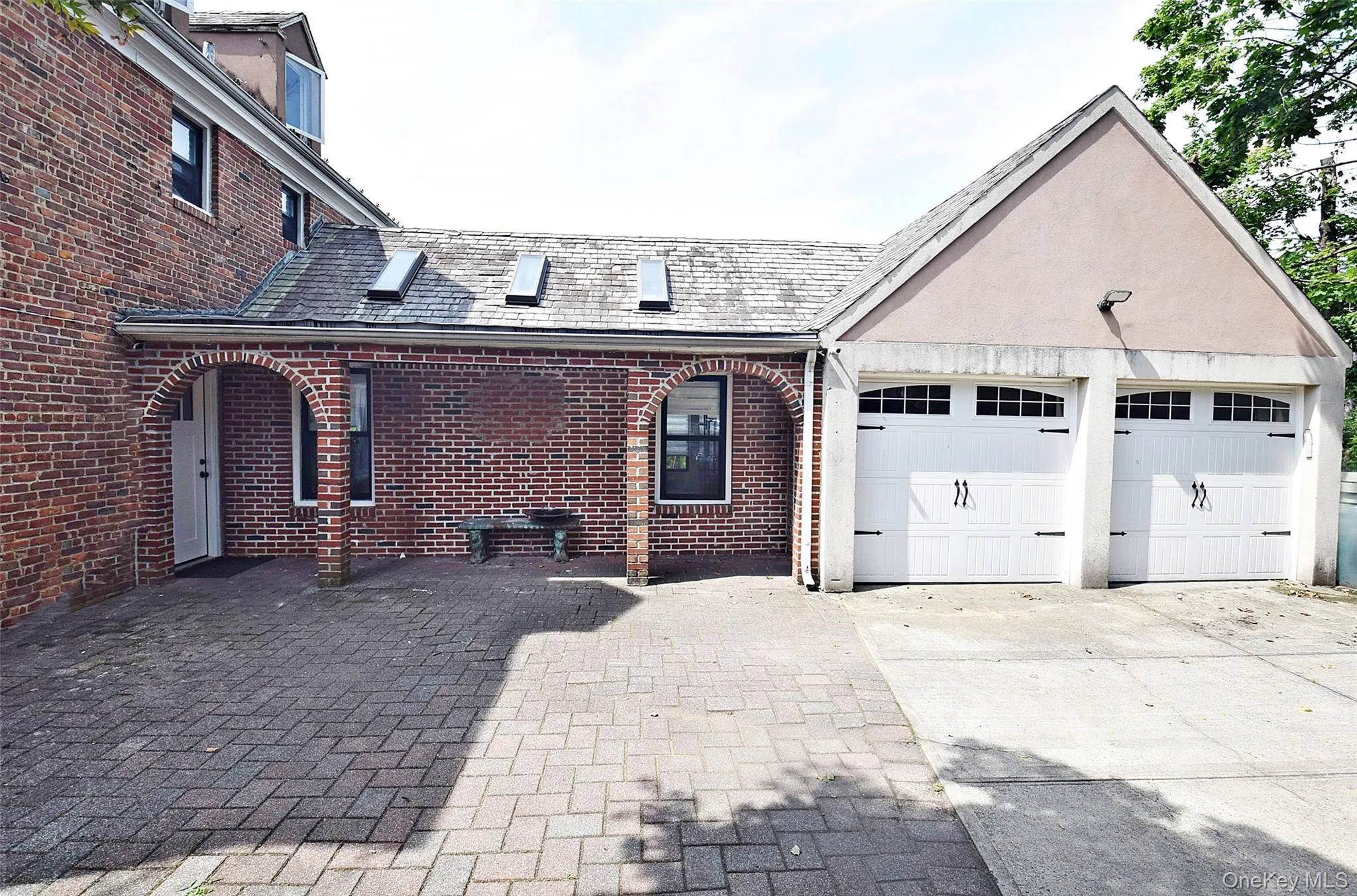 This residential red brick house features a two-car stucco garage connected to the main structure by an arched, skylit covered walkway over a brick-paved driveway. This residential red brick house features a two-car stucco garage connected to the main structure by an arched, skylit covered walkway over a brick-paved driveway.