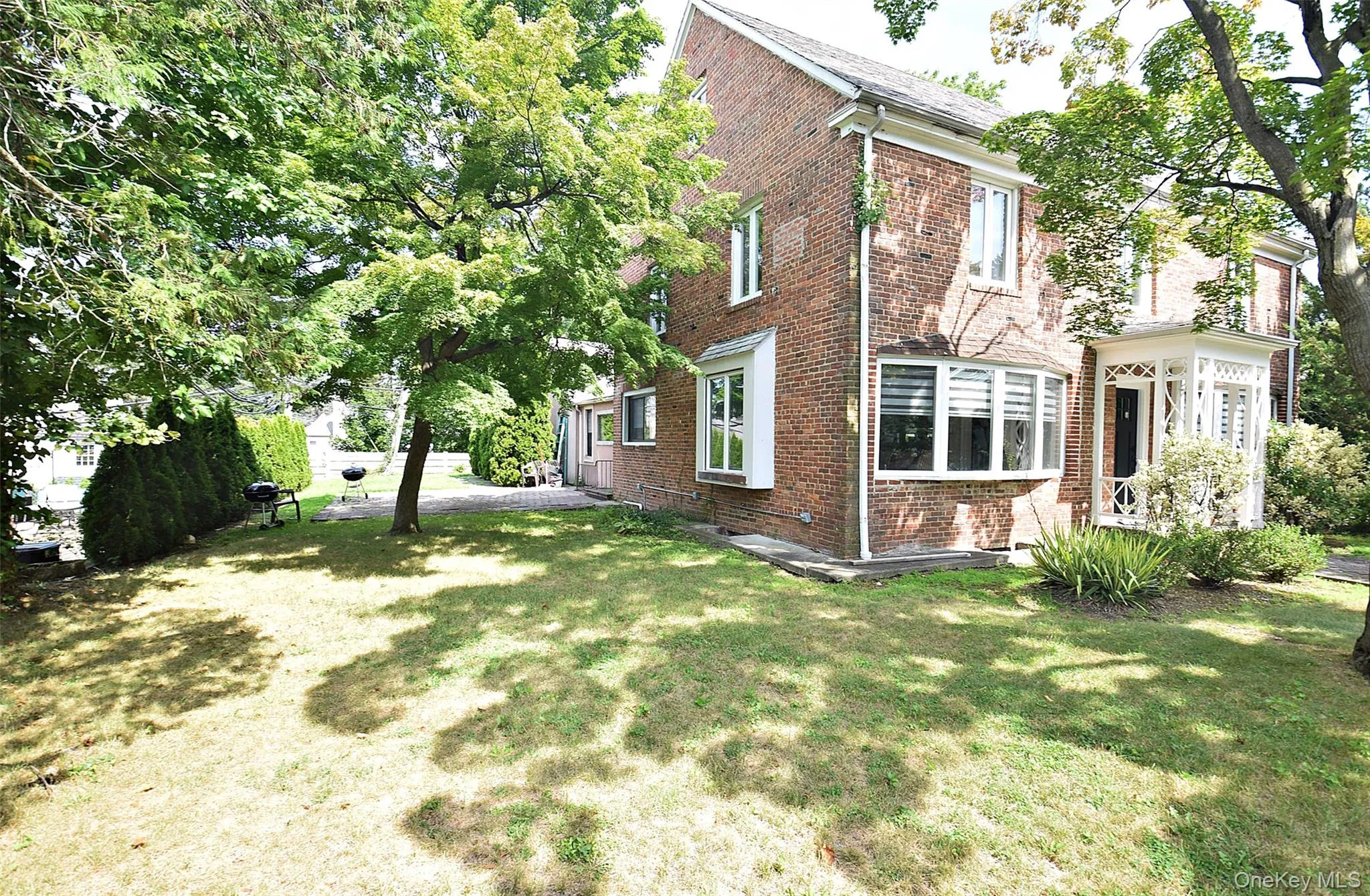 Brick exterior residence featuring multiple windows, a bay window, and a covered front entry with intricate white detailing Brick exterior residence featuring multiple windows, a bay window, and a covered front entry with intricate white detailing