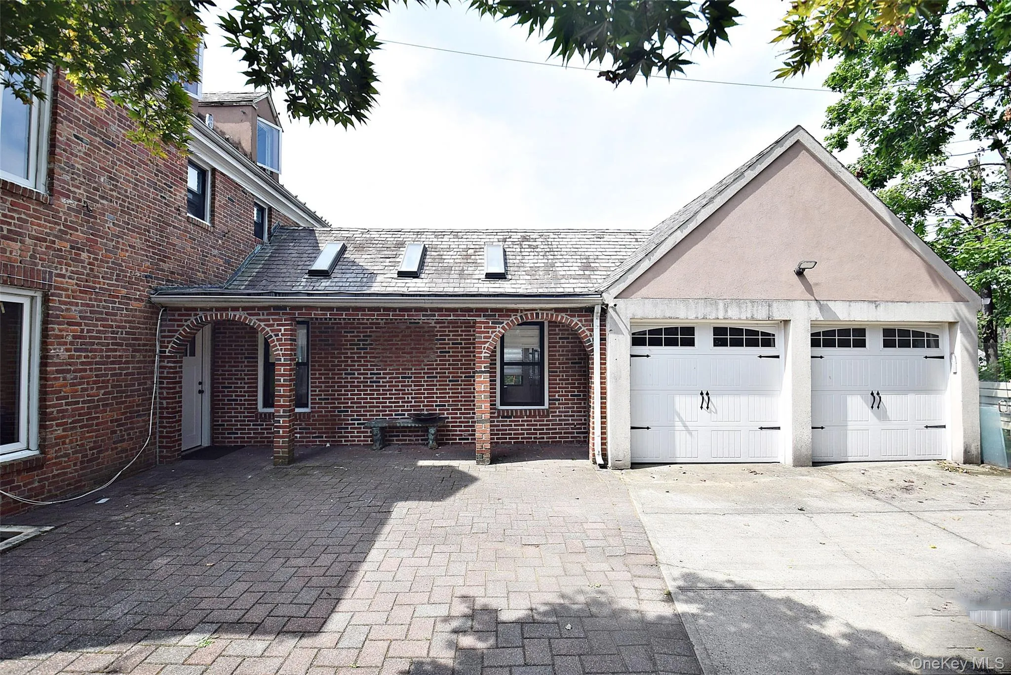 This residential red brick house features a two-car stucco garage connected to the main structure by an arched, skylit covered walkway over a brick-paved driveway. This residential red brick house features a two-car stucco garage connected to the main structure by an arched, skylit covered walkway over a brick-paved driveway.