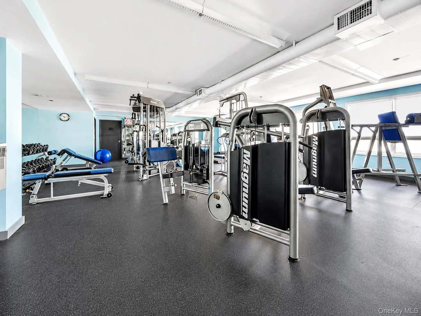 Fitness area featuring rubber flooring, recessed lighting, and blue accent walls Fitness area featuring rubber flooring, recessed lighting, and blue accent walls