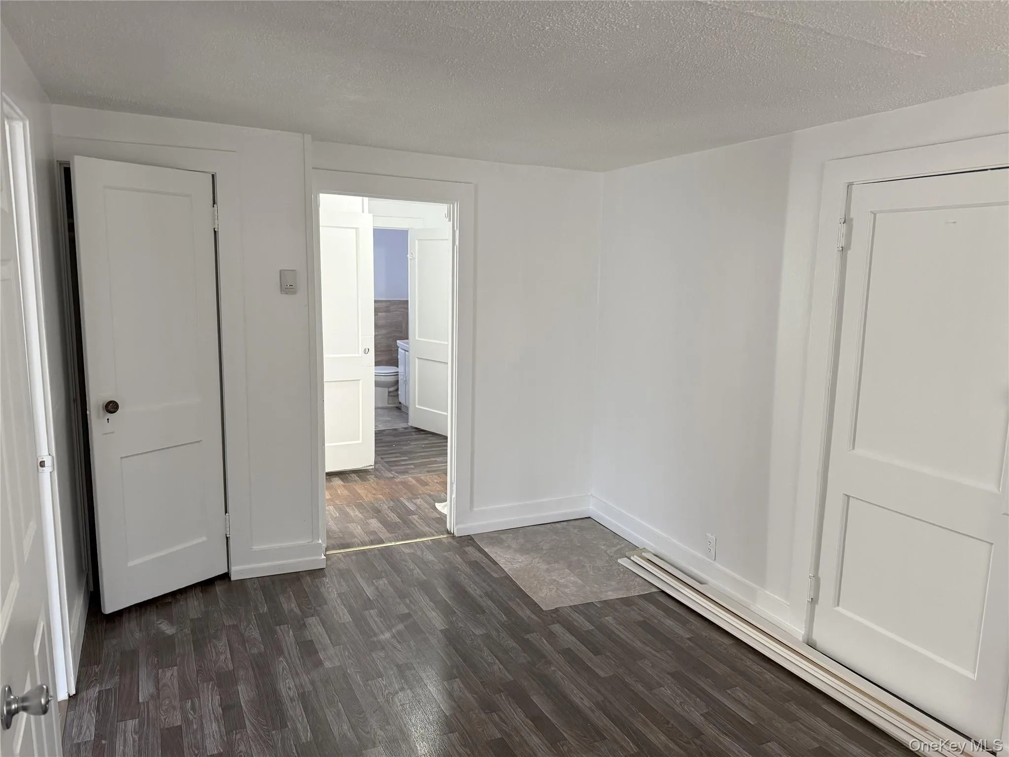 Spare room featuring dark wood-type floors and a textured ceiling Spare room featuring dark wood-type floors and a textured ceiling