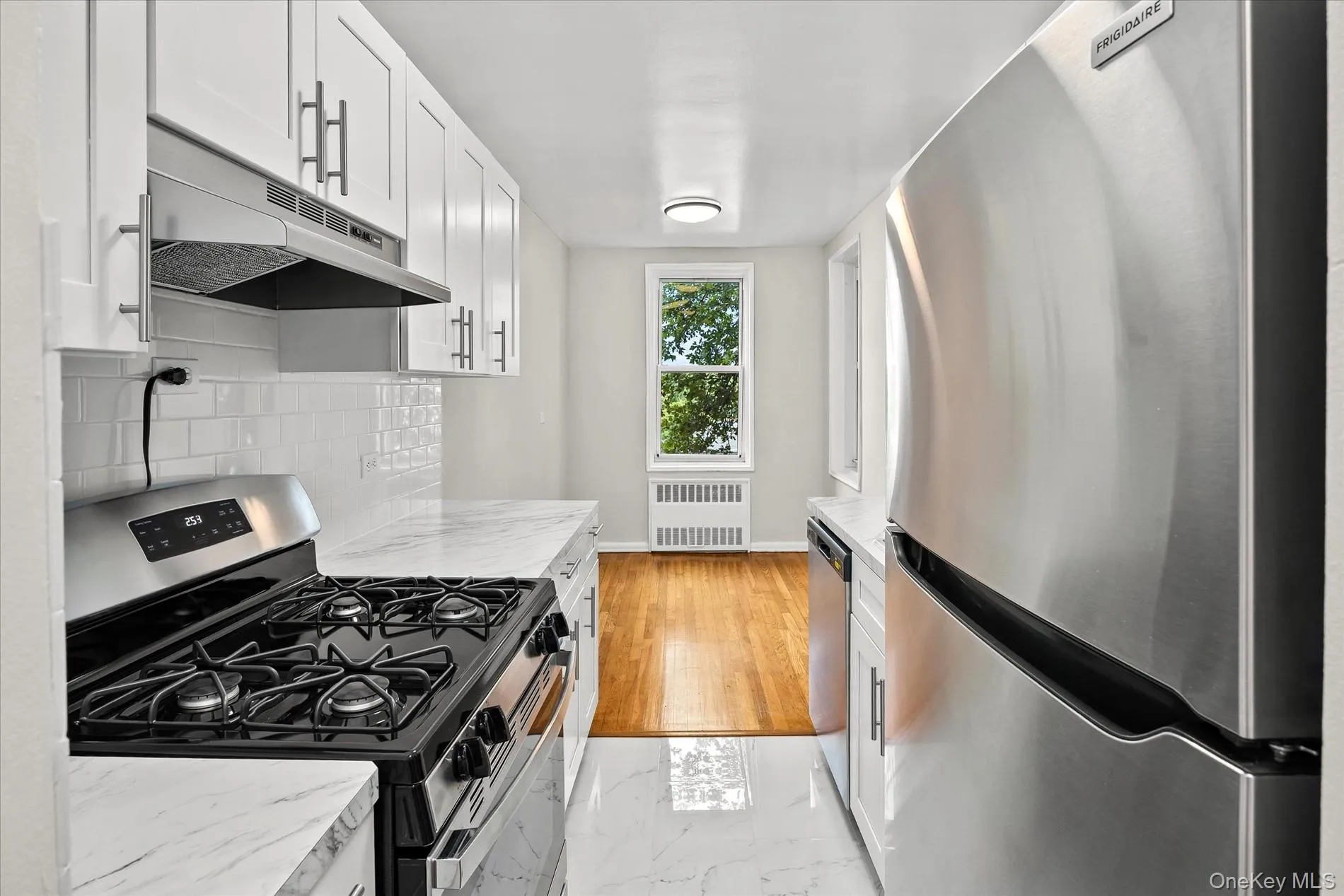 Kitchen featuring white shaker cabinetry, stainless steel appliances, marble-patterned countertops, and white subway tile backsplash Kitchen featuring white shaker cabinetry, stainless steel appliances, marble-patterned countertops, and white subway tile backsplash