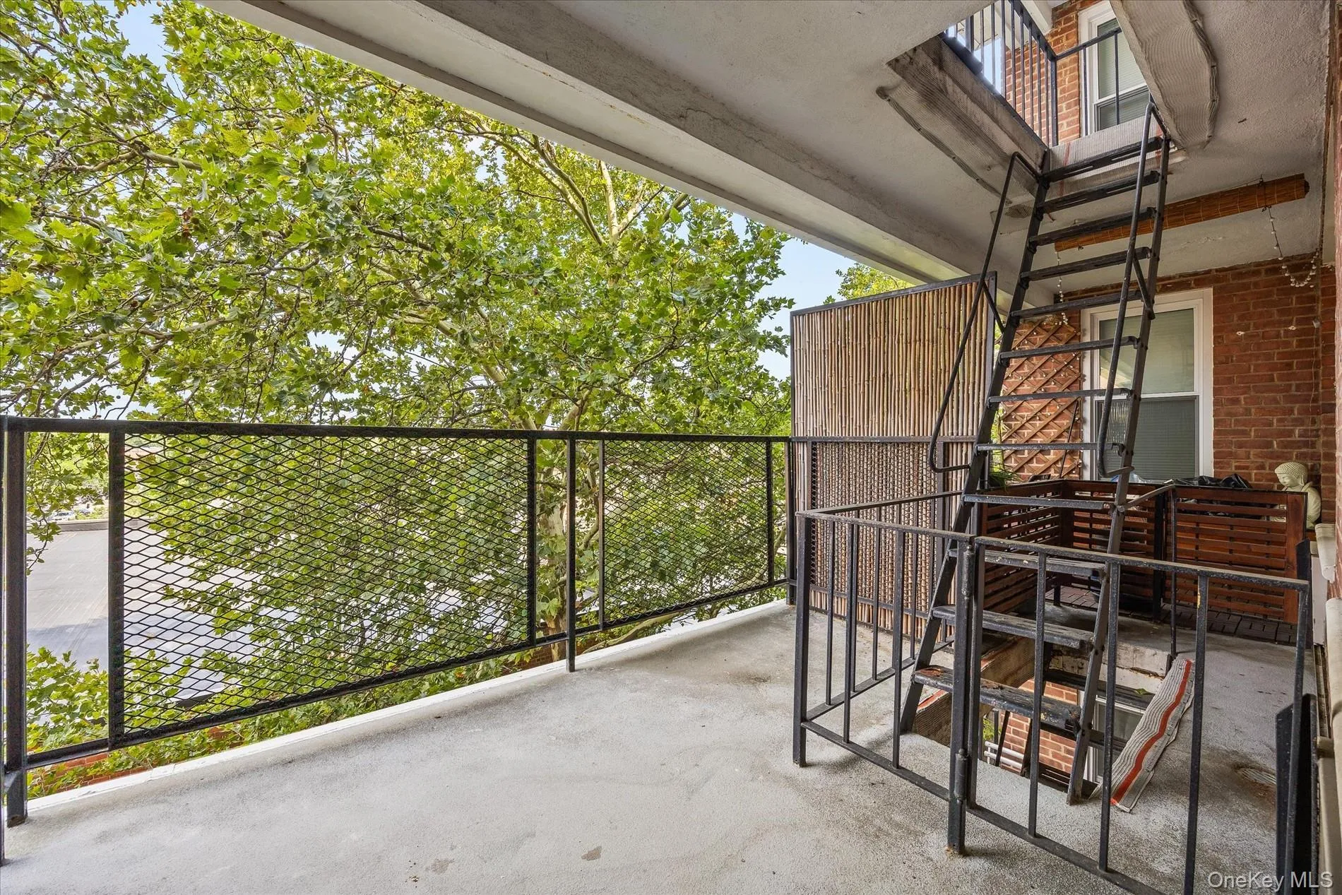 Private balcony with concrete flooring, black metal railing, and a permanent exterior ladder Private balcony with concrete flooring, black metal railing, and a permanent exterior ladder