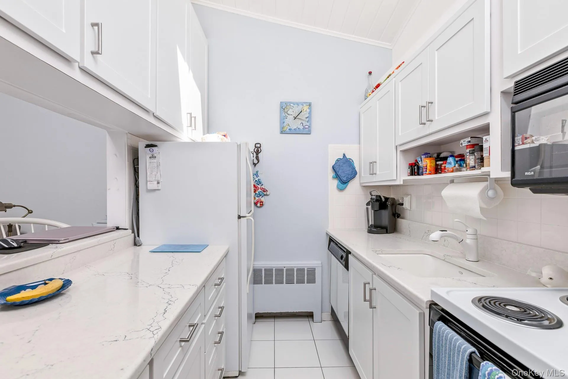 Bright kitchen featuring white cabinetry, quartz countertops, tile flooring, and a vaulted ceiling Bright kitchen featuring white cabinetry, quartz countertops, tile flooring, and a vaulted ceiling