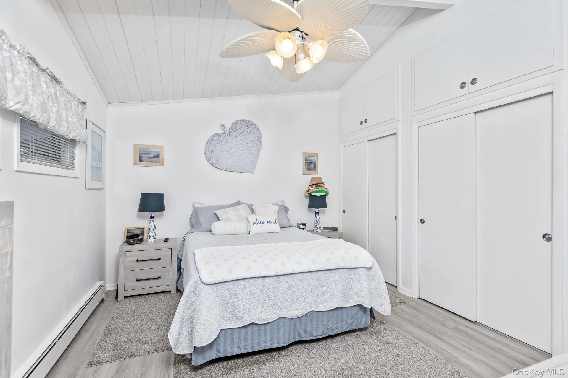 Vaulted ceiling with wood paneling, ceiling fan with integrated lighting, two sliding door closets, and wood-finish flooring Vaulted ceiling with wood paneling, ceiling fan with integrated lighting, two sliding door closets, and wood-finish flooring