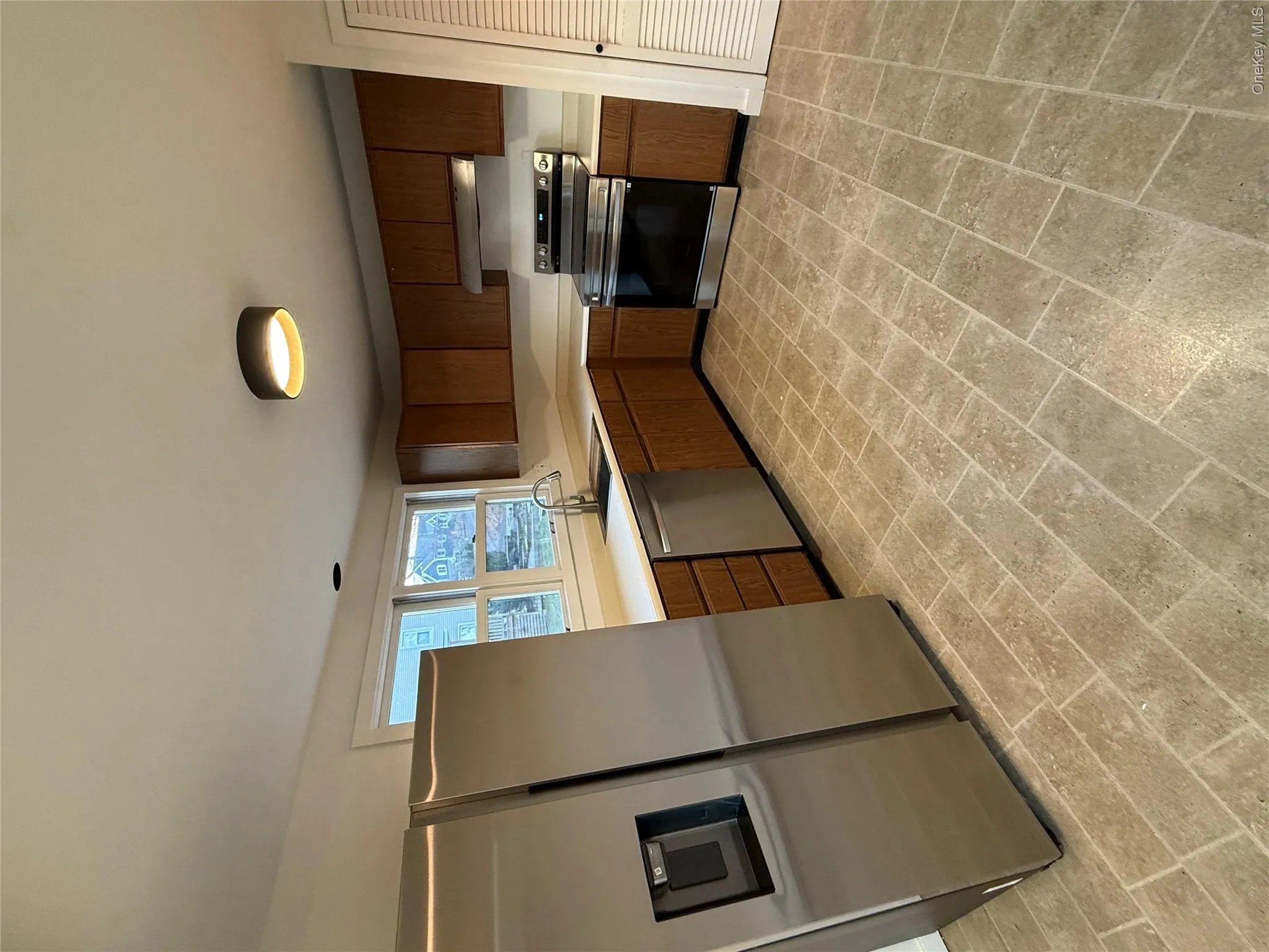 Kitchen with fridge, stove, light countertops, brick patterned floors, and dishwasher Kitchen with fridge, stove, light countertops, brick patterned floors, and dishwasher