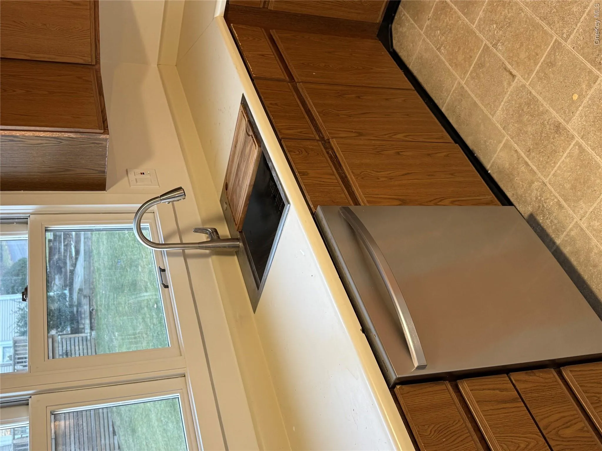 Kitchen featuring dishwashing machine, brown cabinets, and light countertops Kitchen featuring dishwashing machine, brown cabinets, and light countertops