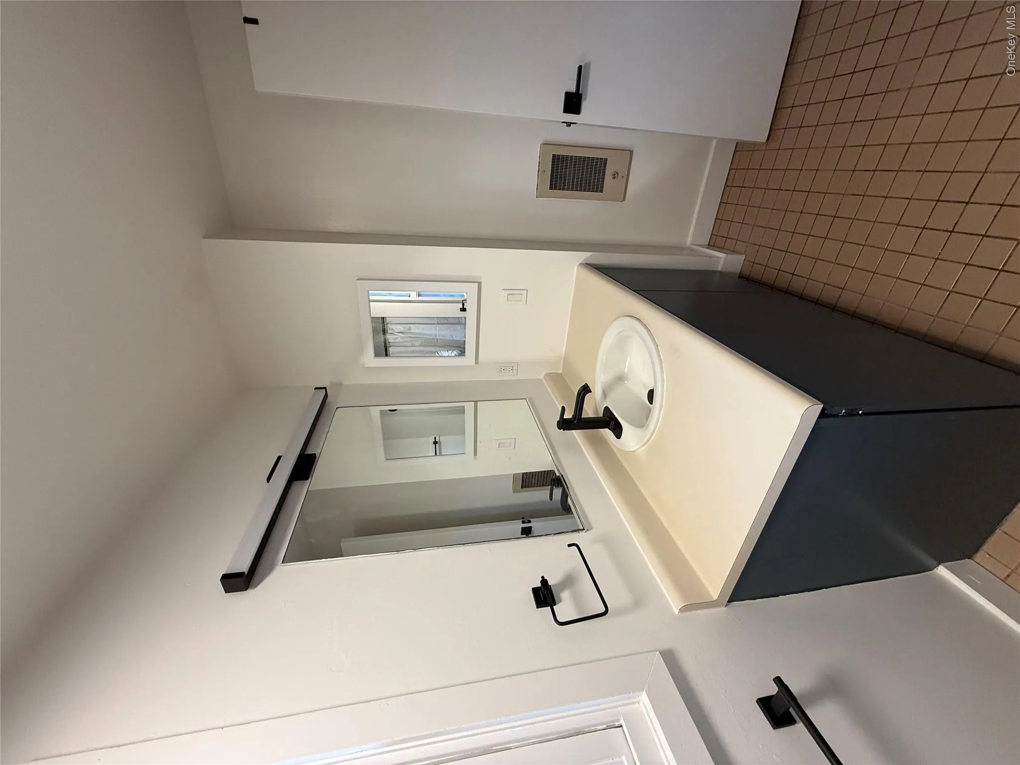 Bathroom with vanity, heating unit, and light tile patterned floors Bathroom with vanity, heating unit, and light tile patterned floors