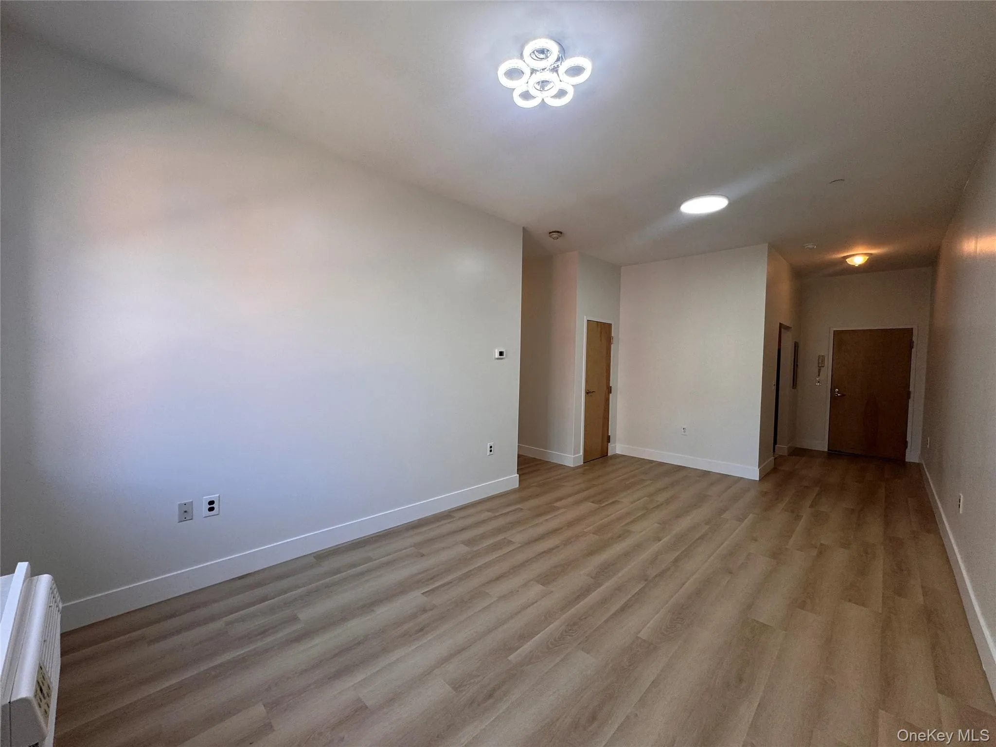 Wood-finish flooring, neutral wall tones, recessed lighting, and a modern ceiling light fixture Wood-finish flooring, neutral wall tones, recessed lighting, and a modern ceiling light fixture