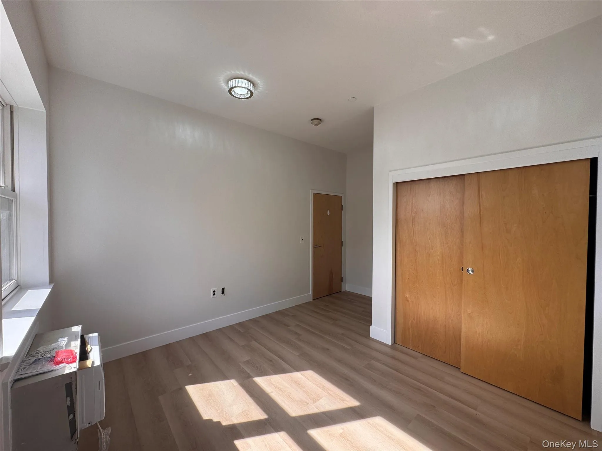 Light wood-finish flooring, white painted walls, and ceiling-mounted lighting Light wood-finish flooring, white painted walls, and ceiling-mounted lighting