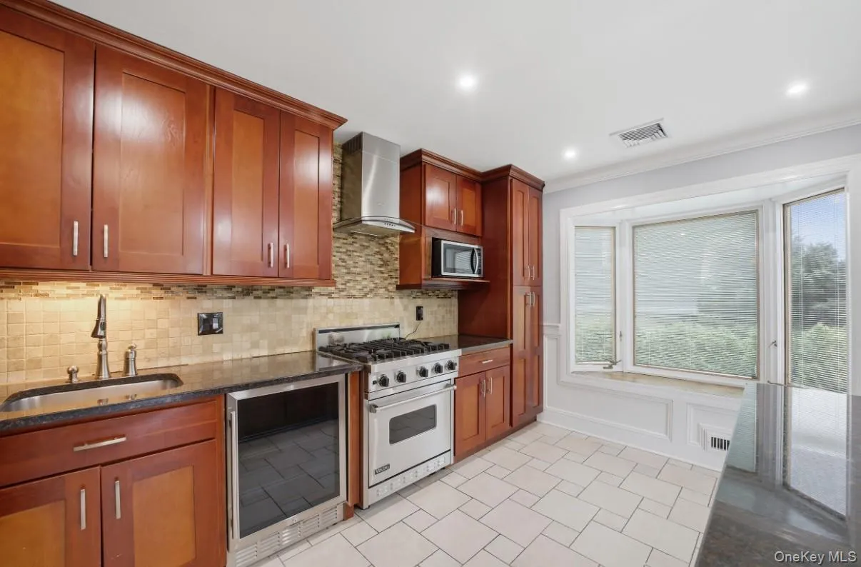 Kitchen features wine fridge, tiled backsplash, granite countertops and plenty of storage. Kitchen features wine fridge, tiled backsplash, granite countertops and plenty of storage.