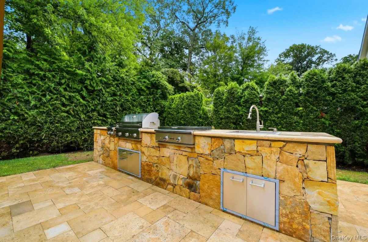 Outdoor kitchen featuring stonework, built-in grill, sink and generous prep space- perfect for dining and entertaining. Outdoor kitchen featuring stonework, built-in grill, sink and generous prep space- perfect for dining and entertaining.