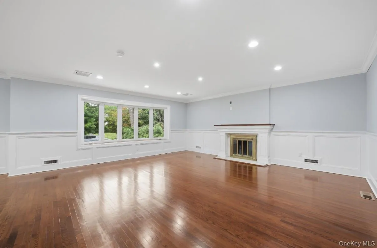 Spacious formal living room with hardwood floors, elegant millwork, and recessed lighting. Spacious formal living room with hardwood floors, elegant millwork, and recessed lighting.
