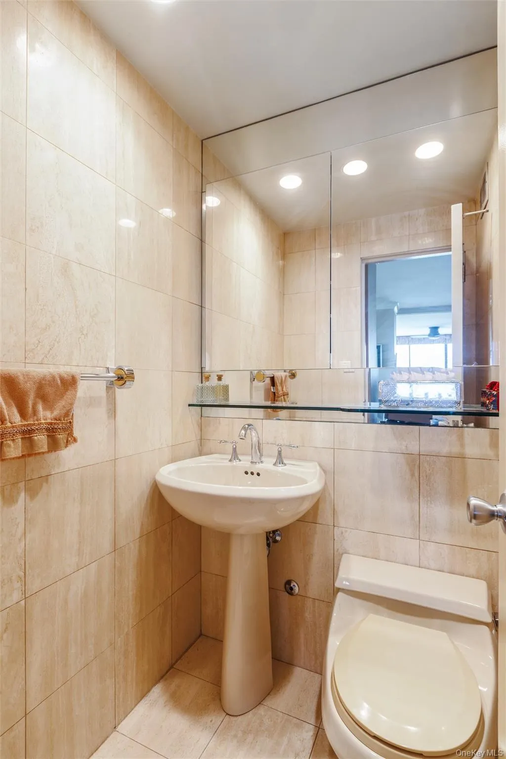 Pedestal sink with chrome faucet, wall-mounted mirror, recessed lighting, and tiled walls Pedestal sink with chrome faucet, wall-mounted mirror, recessed lighting, and tiled walls