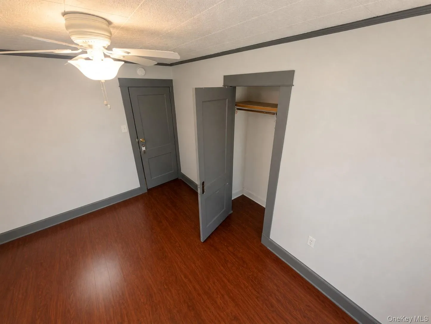 Wood-finish flooring, ceiling fan with integrated lighting, painted trim, painted doors, and a closet with a built-in shelf and hanging rod Wood-finish flooring, ceiling fan with integrated lighting, painted trim, painted doors, and a closet with a built-in shelf and hanging rod