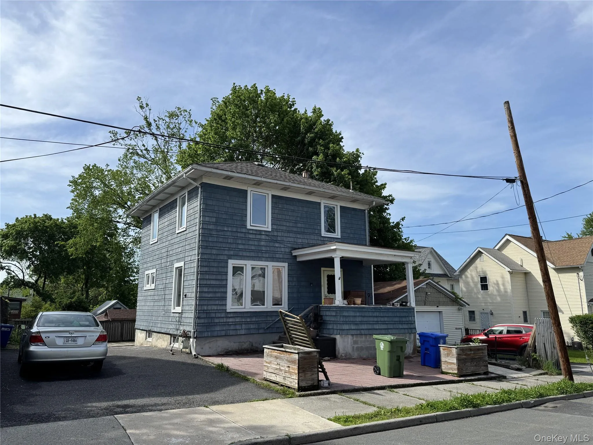 Two-story residence featuring blue shingle siding, white trim windows, and a covered porch with white columns Two-story residence featuring blue shingle siding, white trim windows, and a covered porch with white columns