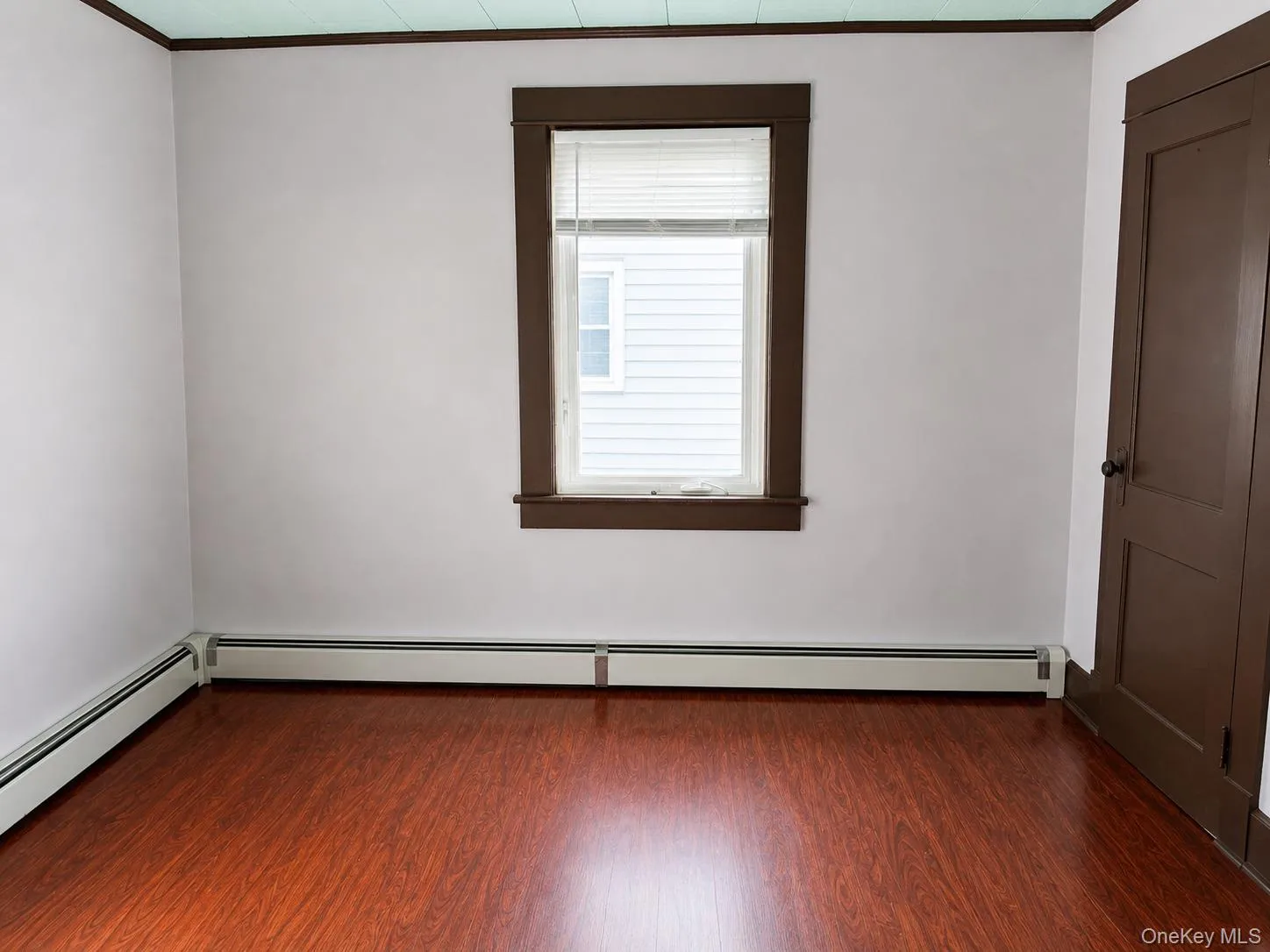 Wood-finish flooring, white walls, and a window with blinds Wood-finish flooring, white walls, and a window with blinds