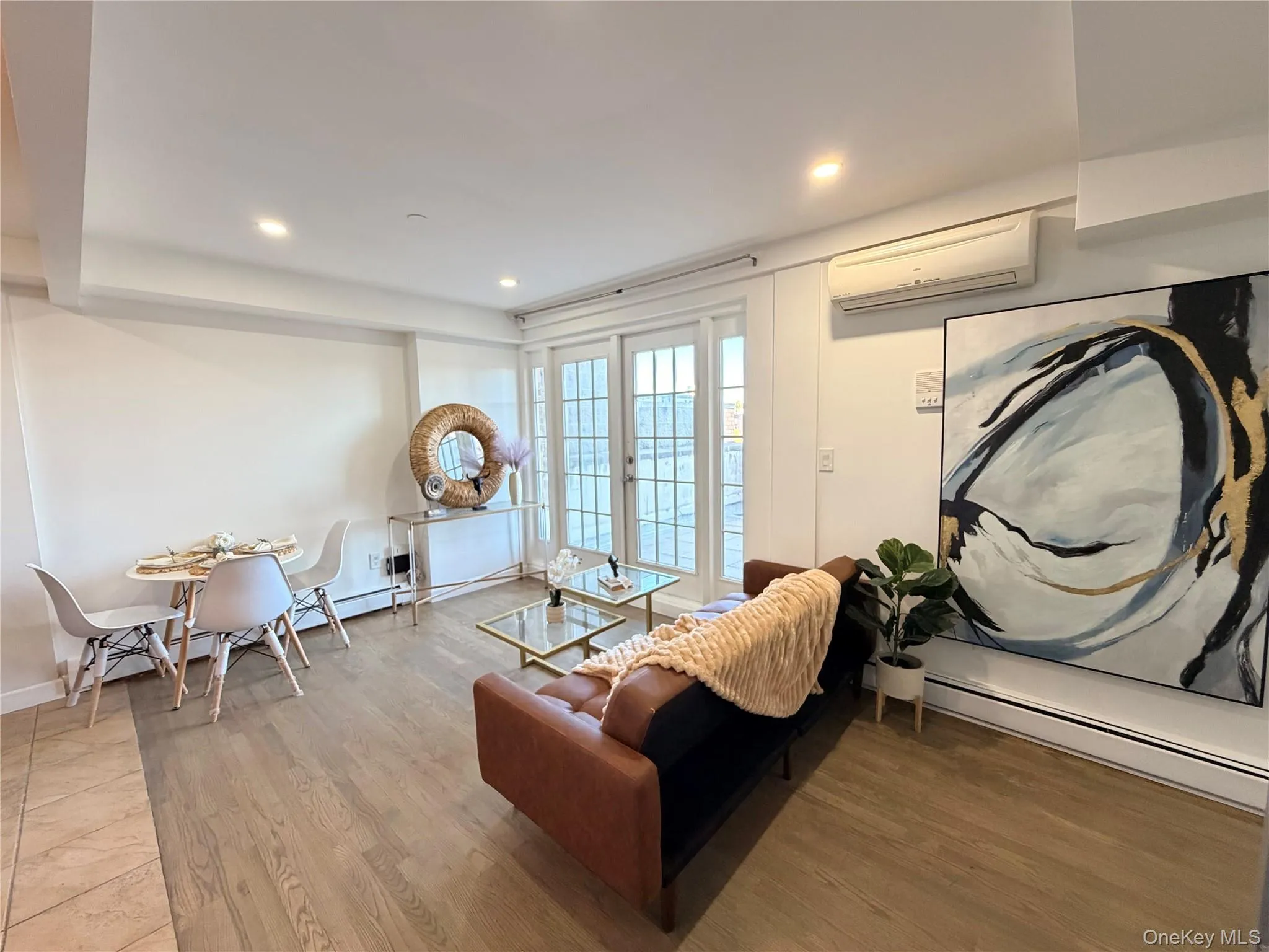 Living area with a baseboard radiator, french doors, a wall mounted air conditioner, wood finished floors, and recessed lighting Living area with a baseboard radiator, french doors, a wall mounted air conditioner, wood finished floors, and recessed lighting