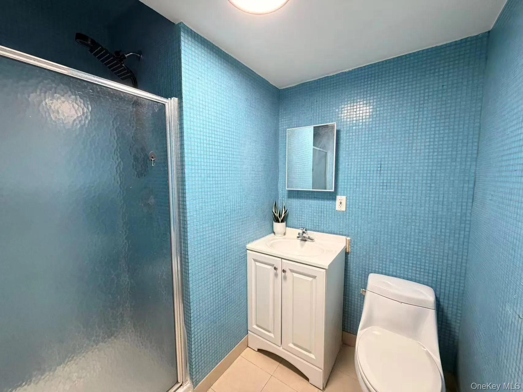 Bathroom featuring light tile patterned floors, a stall shower, and vanity Bathroom featuring light tile patterned floors, a stall shower, and vanity