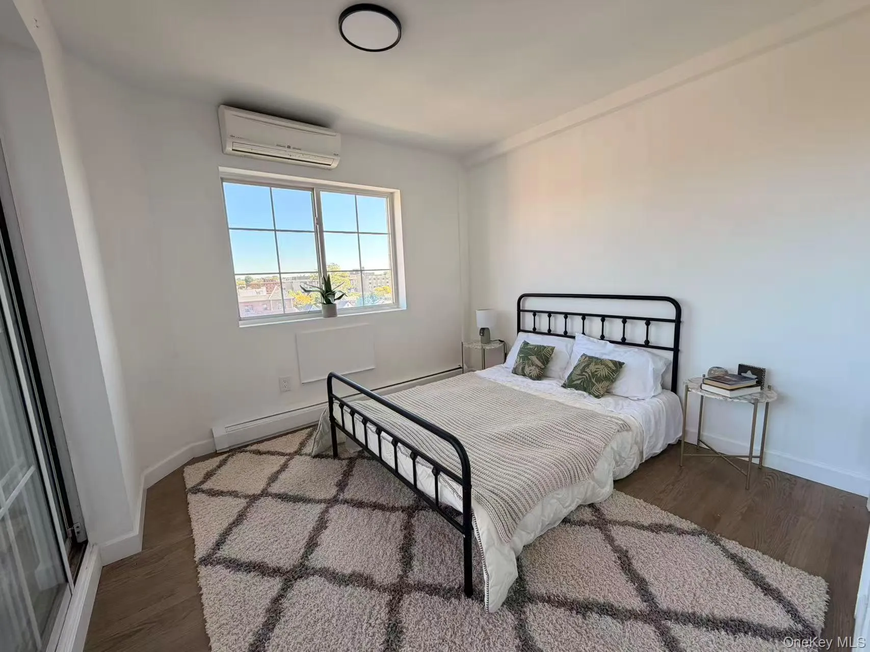 Bedroom featuring dark wood-type flooring and a wall mounted air conditioner Bedroom featuring dark wood-type flooring and a wall mounted air conditioner