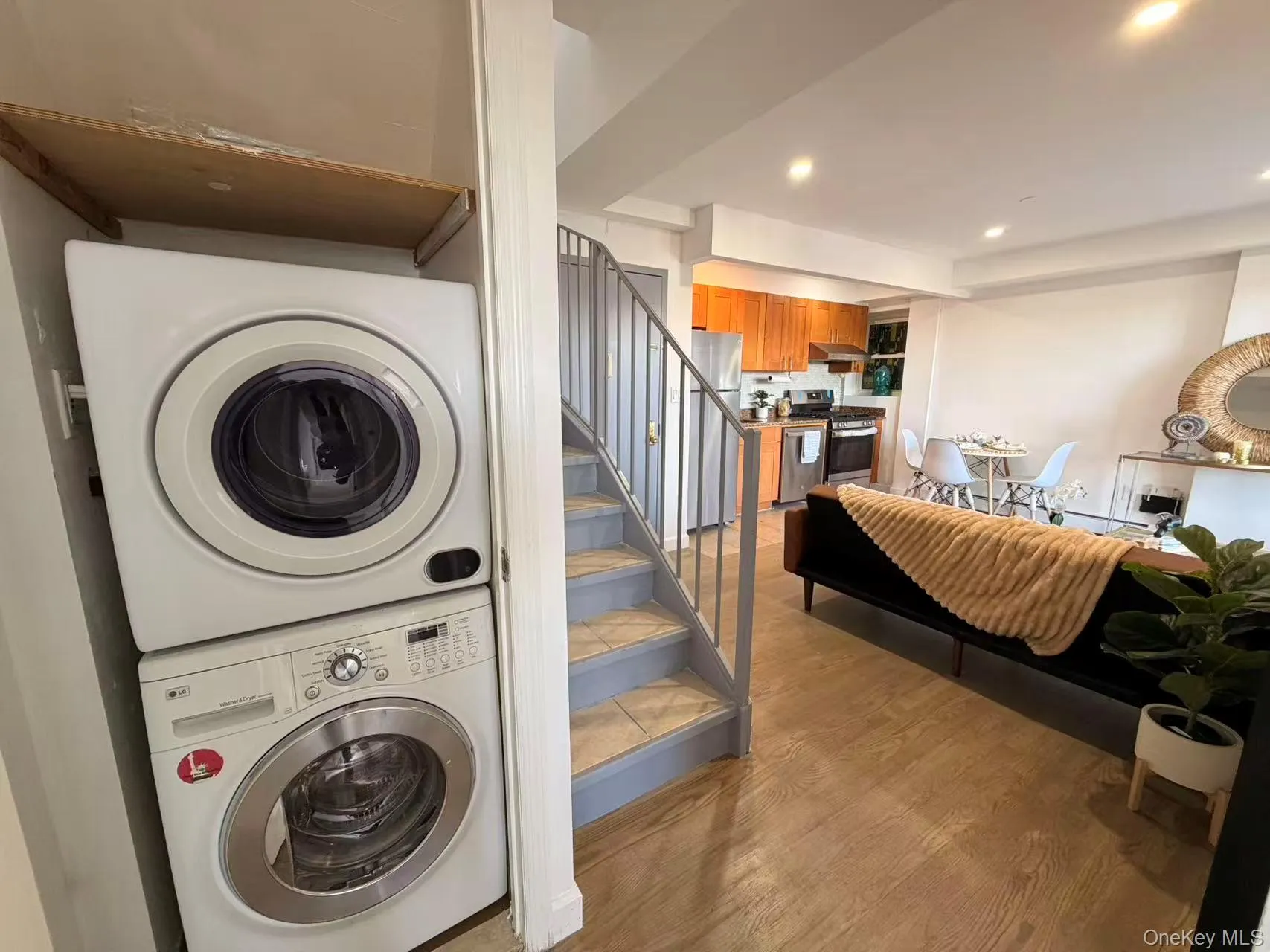 Washroom with light wood-style flooring, recessed lighting, and stacked washing machine and dryer Washroom with light wood-style flooring, recessed lighting, and stacked washing machine and dryer