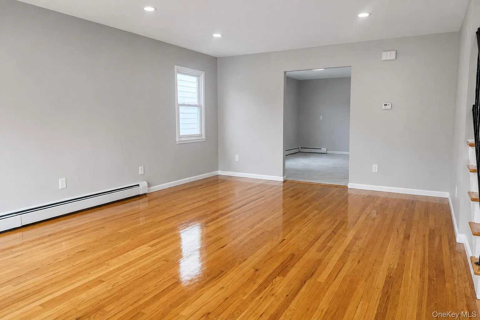 Hardwood flooring, recessed ceiling lighting, a staircase with a black metal railing, two-panel sliding closet doors, and a window Hardwood flooring, recessed ceiling lighting, a staircase with a black metal railing, two-panel sliding closet doors, and a window