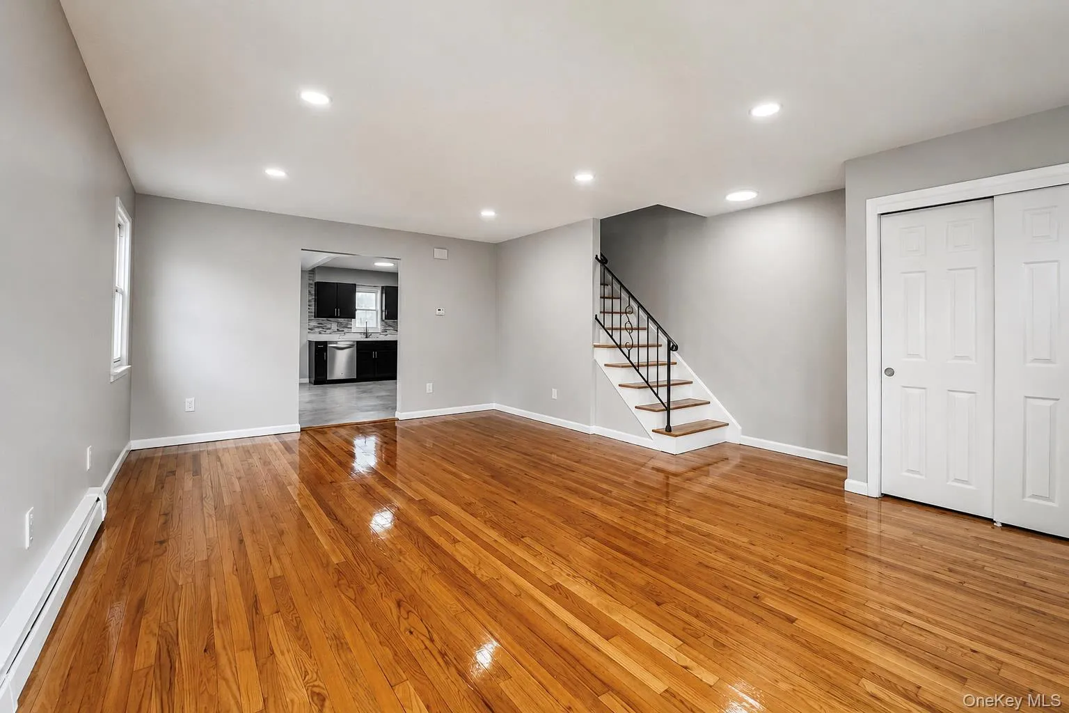 Hardwood flooring, recessed ceiling lighting, a staircase with a black metal railing, two-panel sliding closet doors, and a window Hardwood flooring, recessed ceiling lighting, a staircase with a black metal railing, two-panel sliding closet doors, and a window