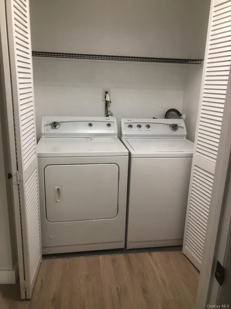 Dedicated laundry closet featuring louvered bi-fold doors, a full size washer and dryer, and a wire storage shelf. Dedicated laundry closet featuring louvered bi-fold doors, a full size washer and dryer, and a wire storage shelf.